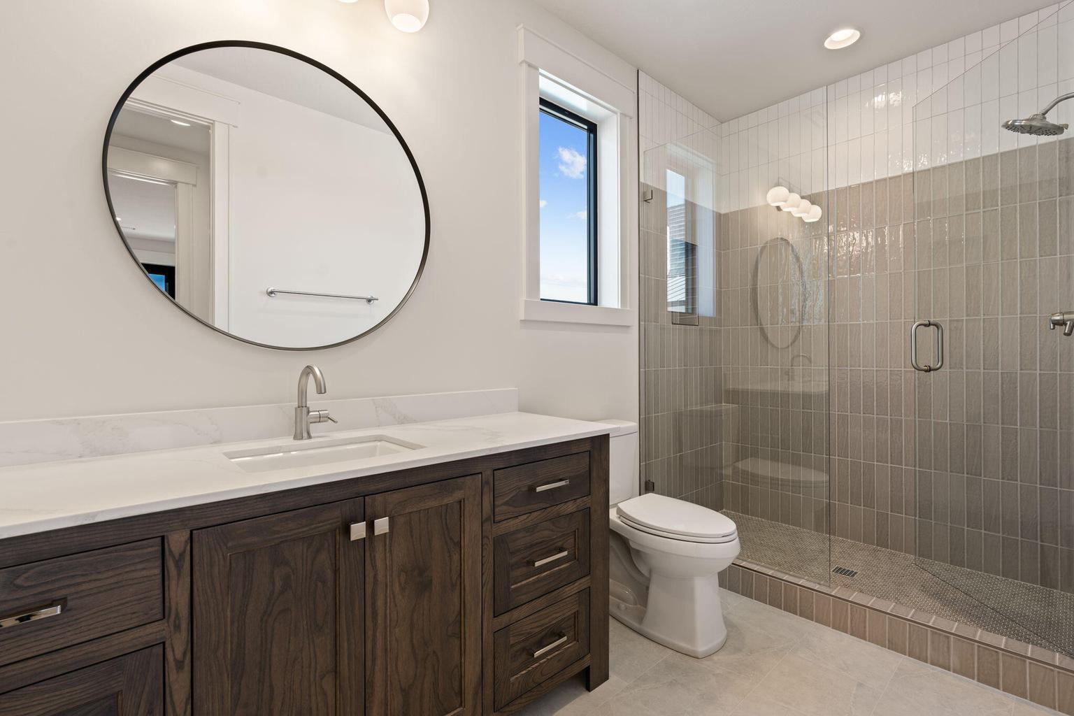 Modern bathroom featuring a wood-finish vanity with a white countertop and integrated sink