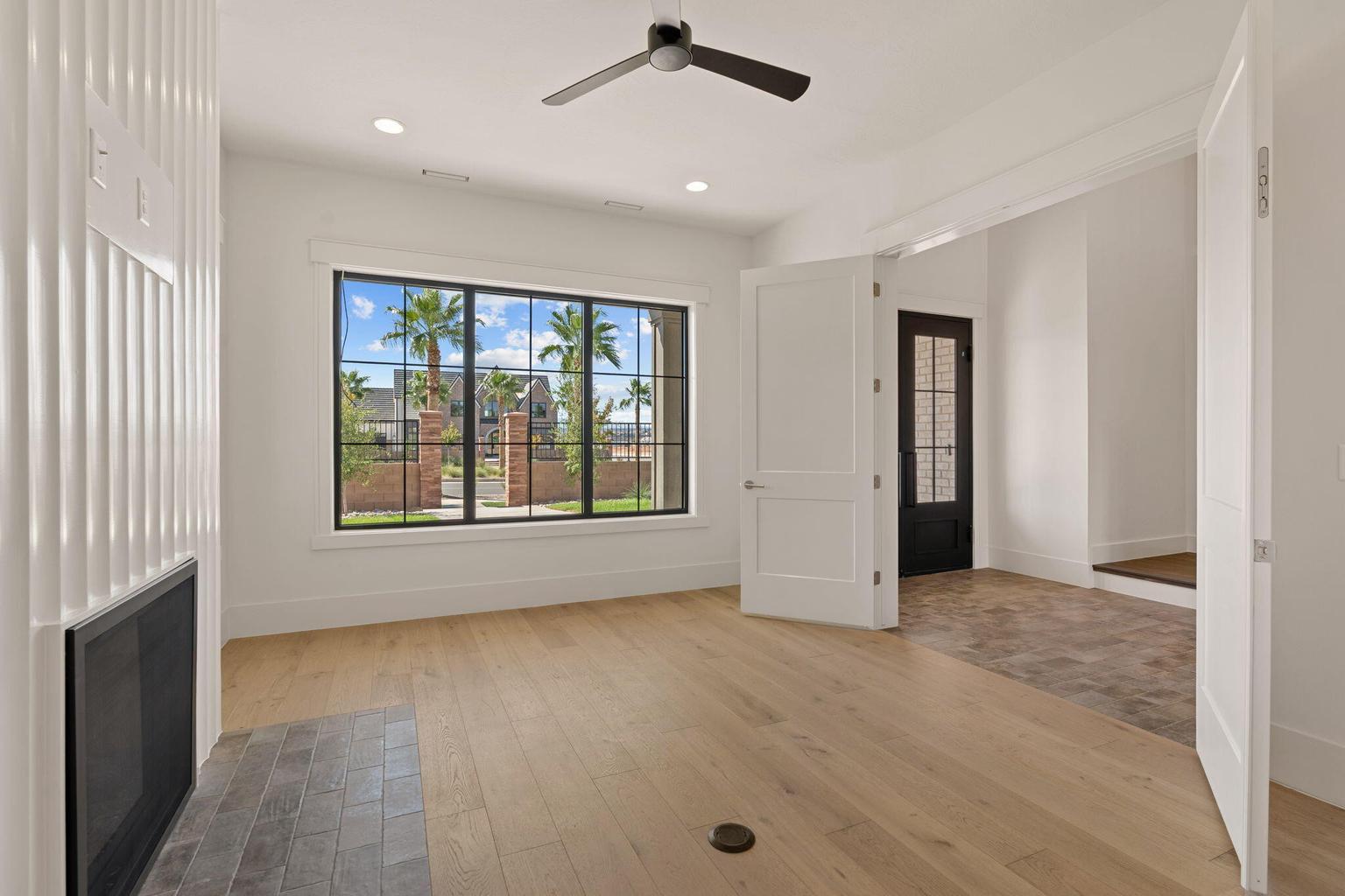 Bright room featuring wood-finish flooring, a contemporary fireplace with a tiled hearth, and a large window with black framing