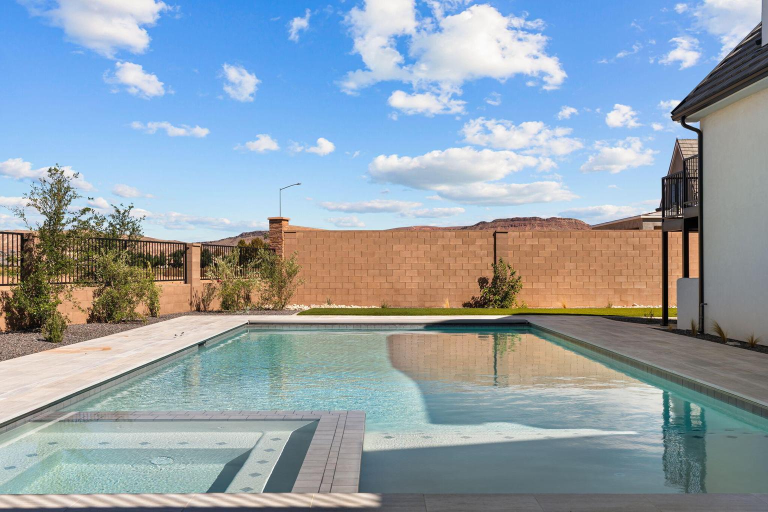 Rectangular swimming pool with integrated spa and light-colored coping