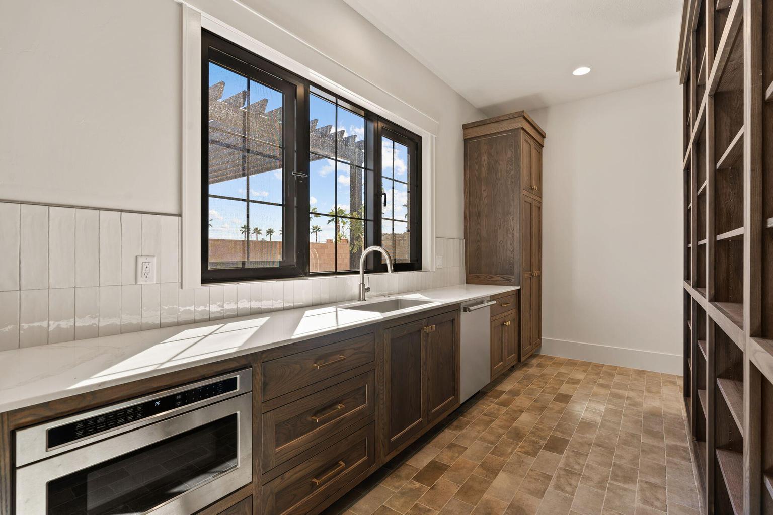 Kitchenette featuring a stainless steel under-counter microwave, a stainless steel dishwasher, and a single basin sink with a gooseneck faucet