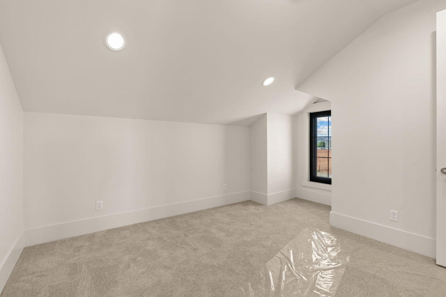 Room featuring sloped ceilings, recessed lighting, neutral carpeting, and white baseboards