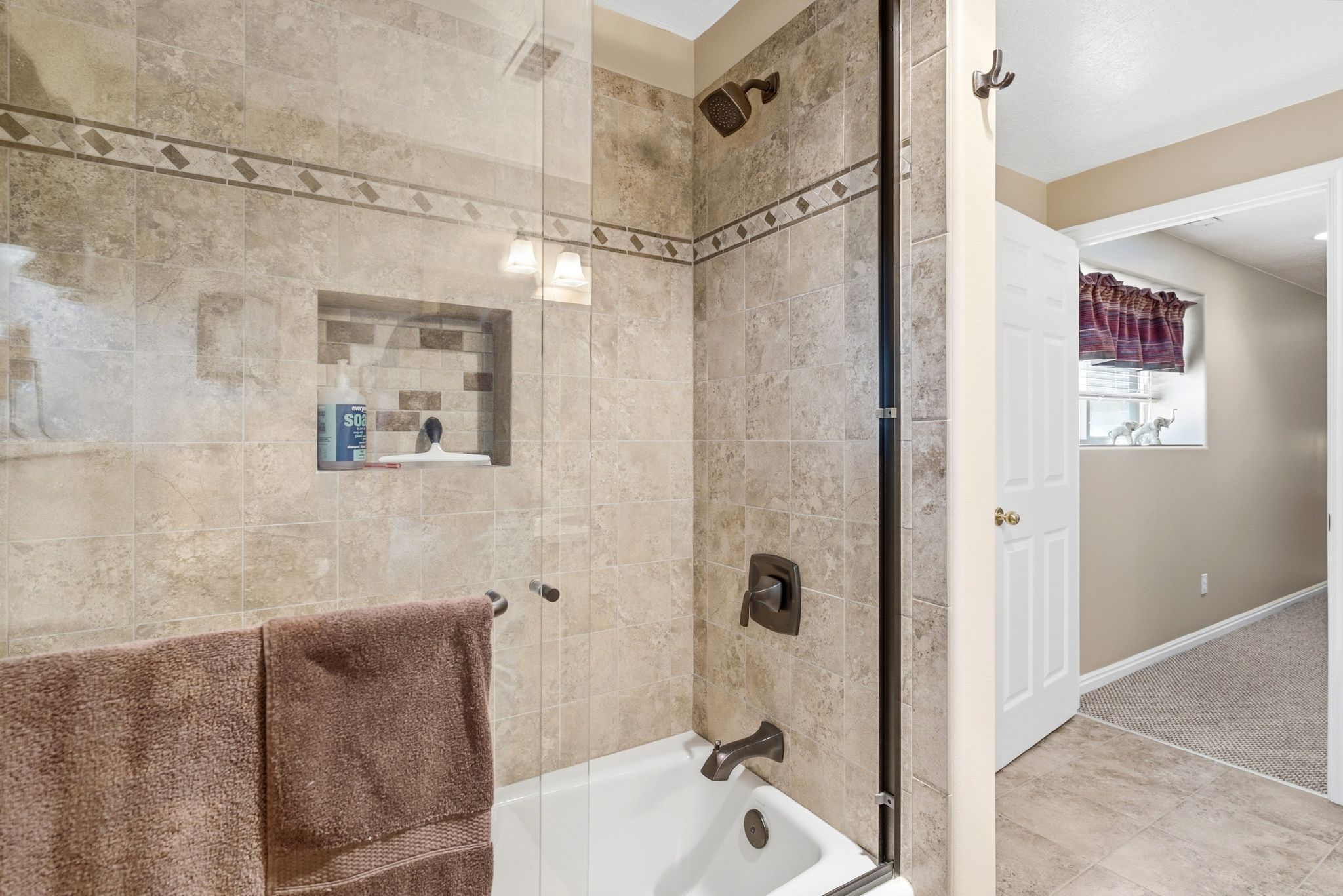 lower level bathroom suiteTiled shower with glass enclosure, built-in niche, and oil-rubbed bronze fixtures