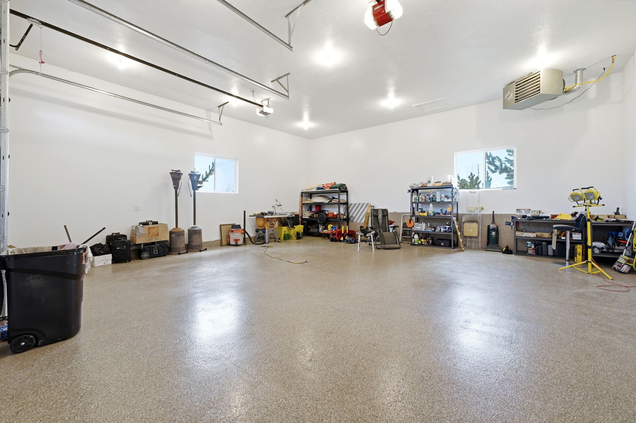 Expansive garage featuring a speckled epoxy floor, multiple windows for natural light, and overhead lighting fixtures