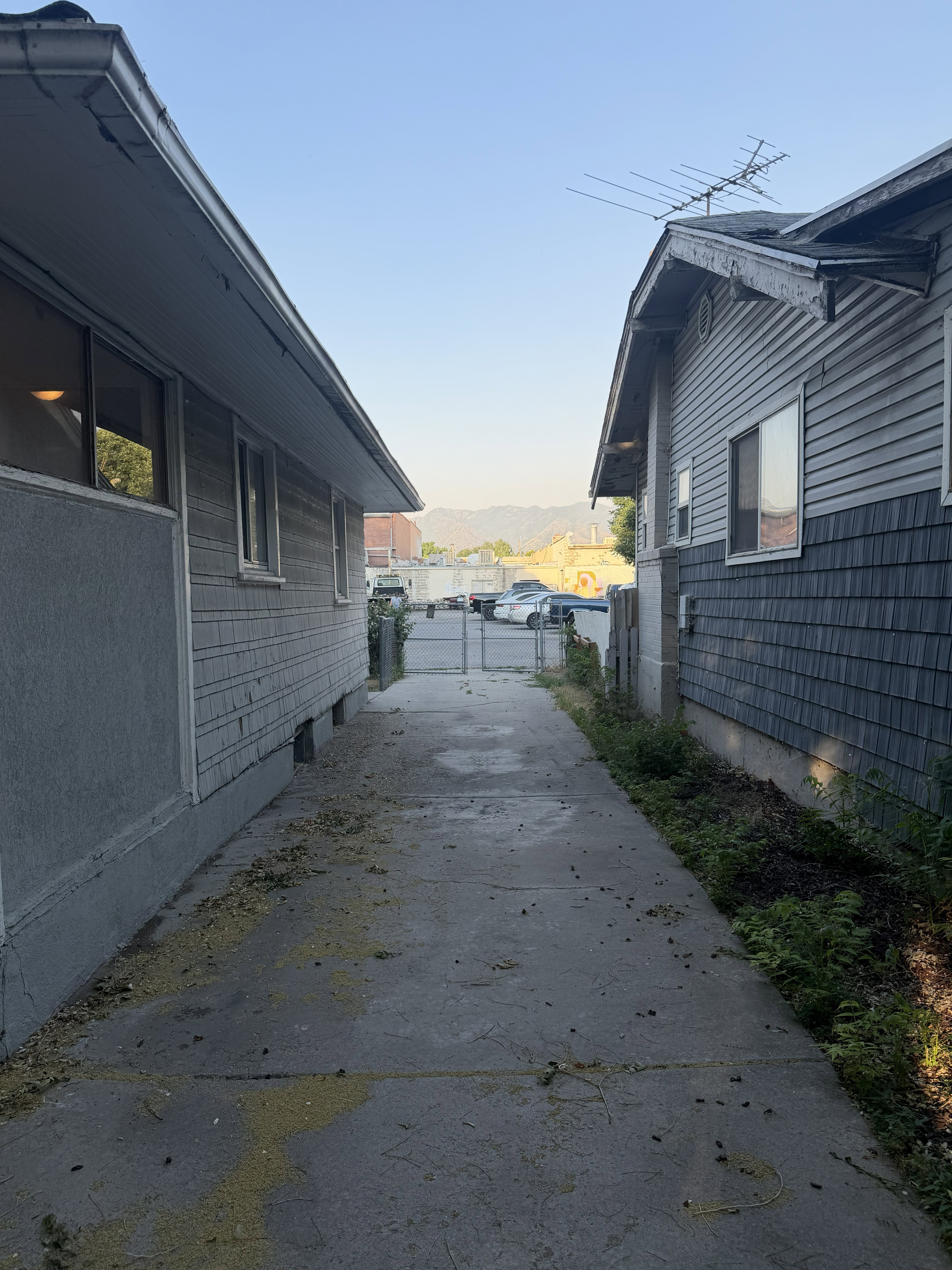 Concrete walkway between two structures with horizontal siding and shingle accents