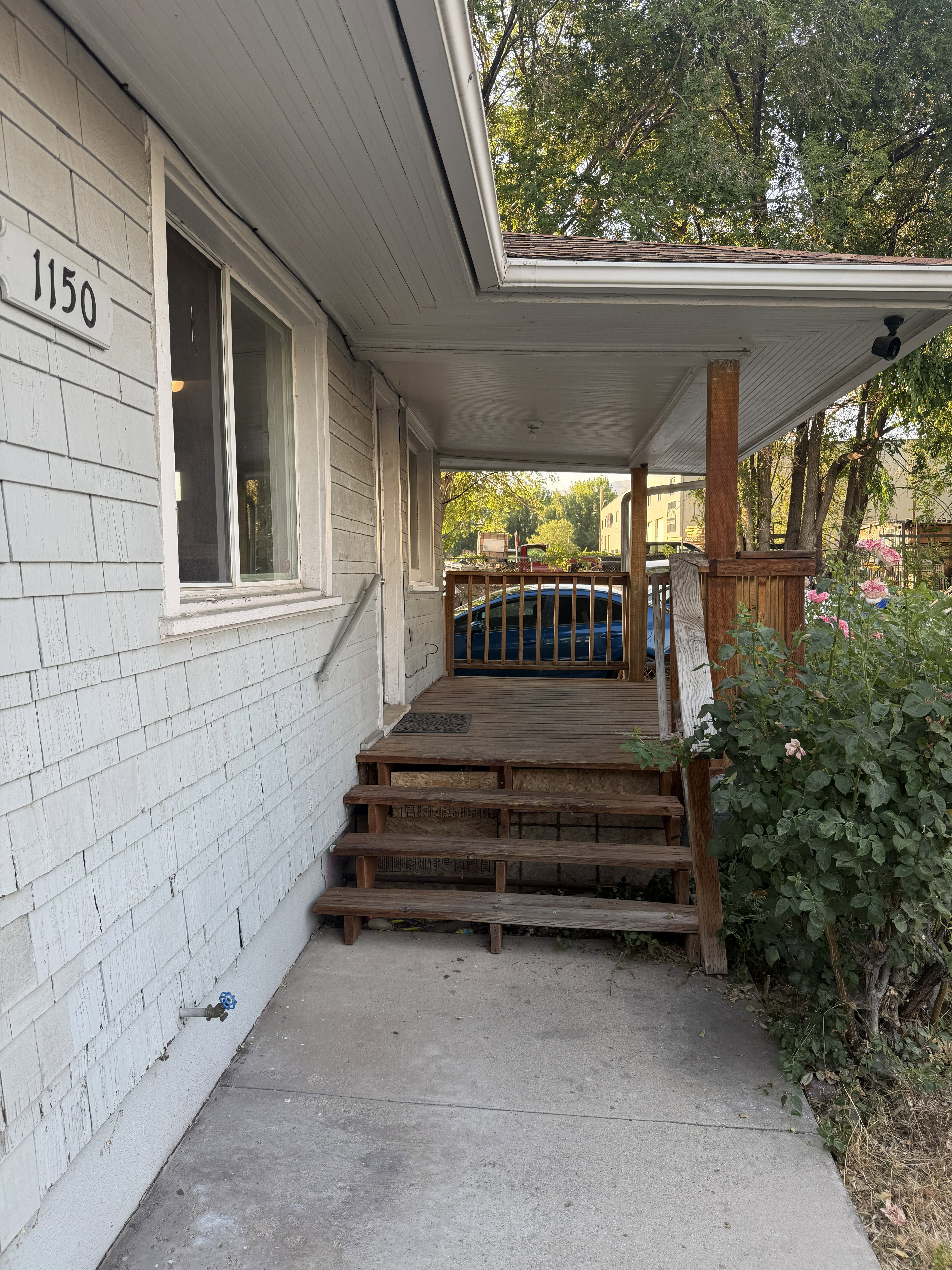 Covered porch entry featuring a multi-level wood deck and concrete pathway