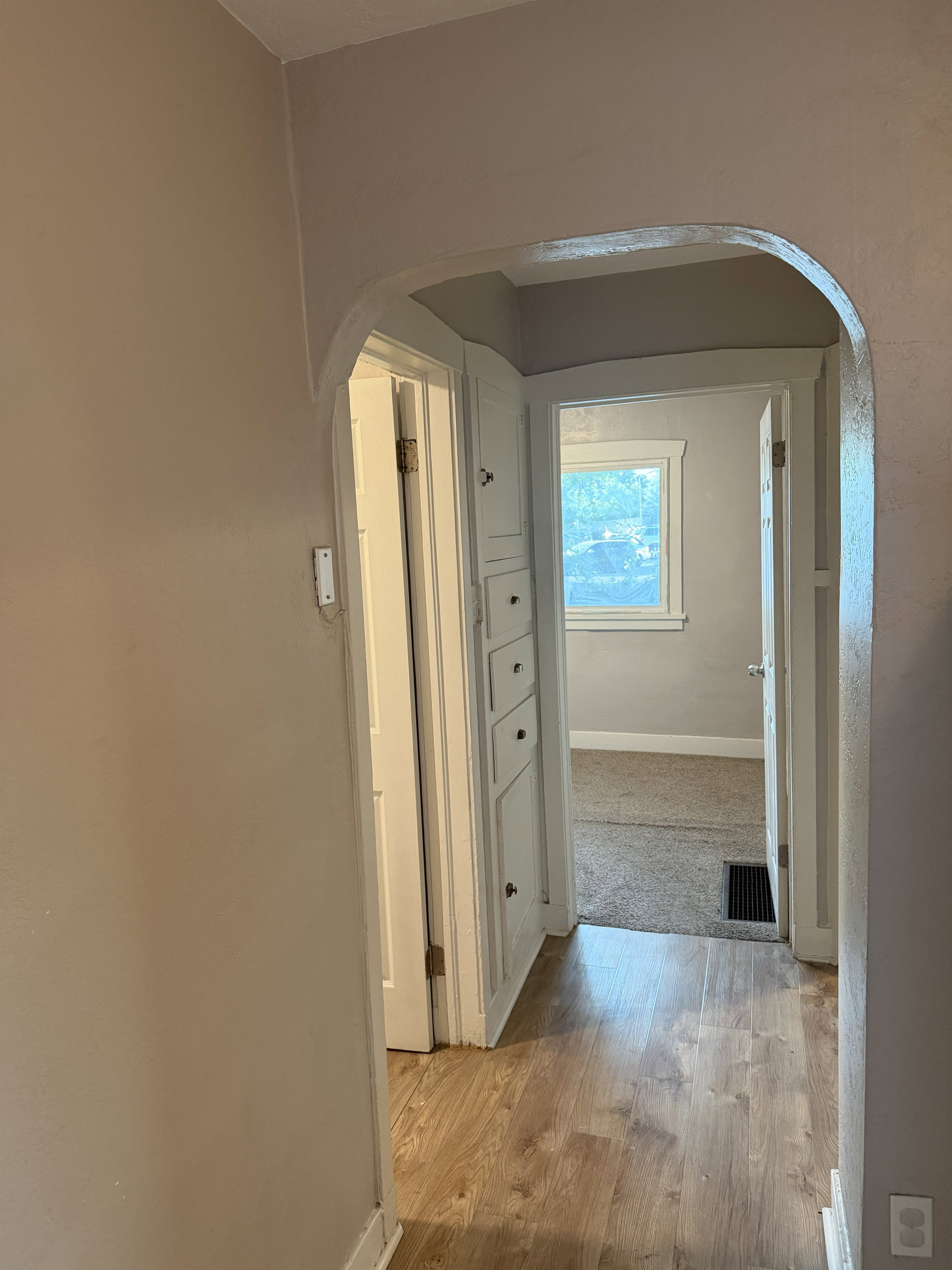 Hallway with light wood-finish flooring and an arched doorway