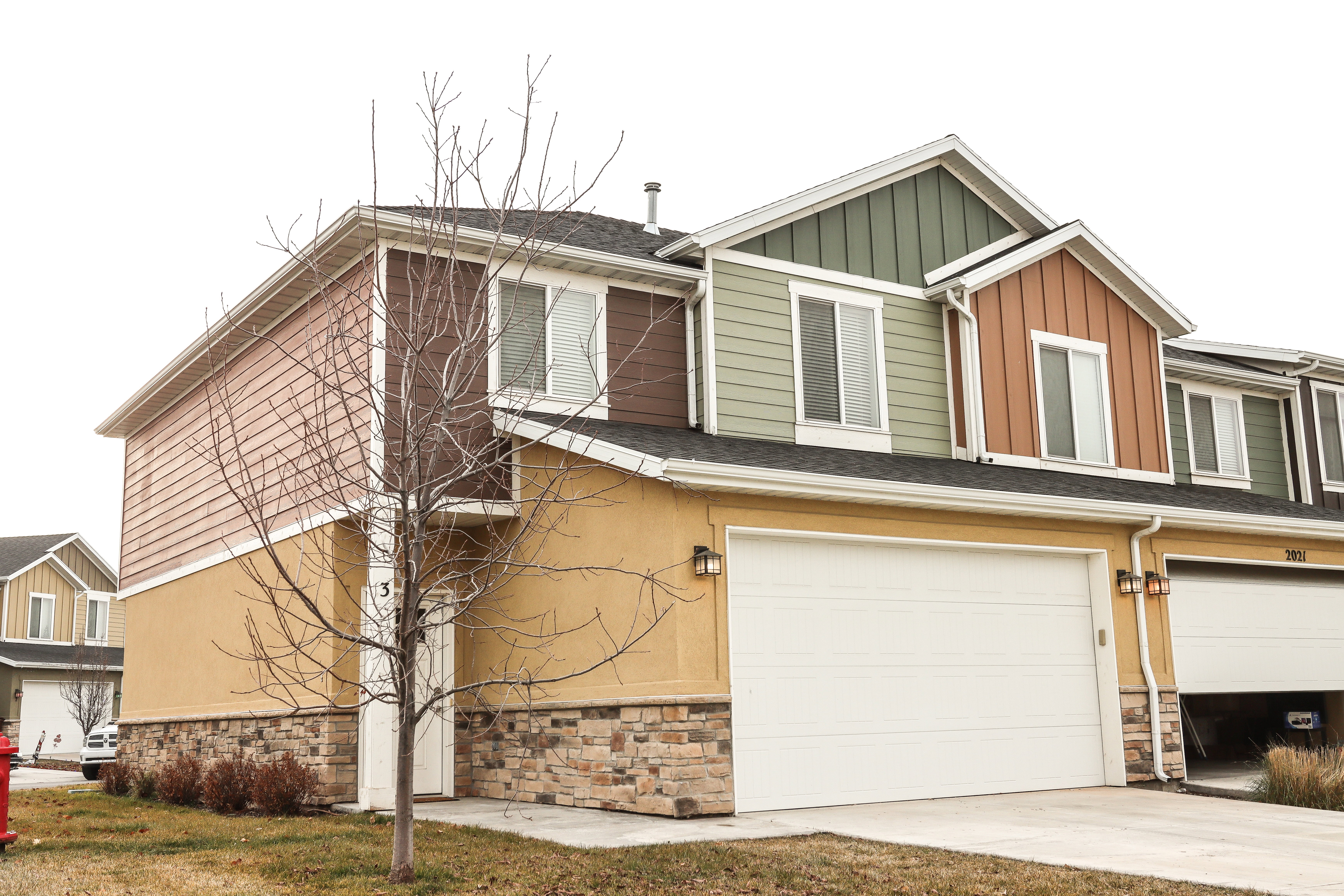 Multi-level townhome featuring a stone and stucco base with varied siding on upper levels