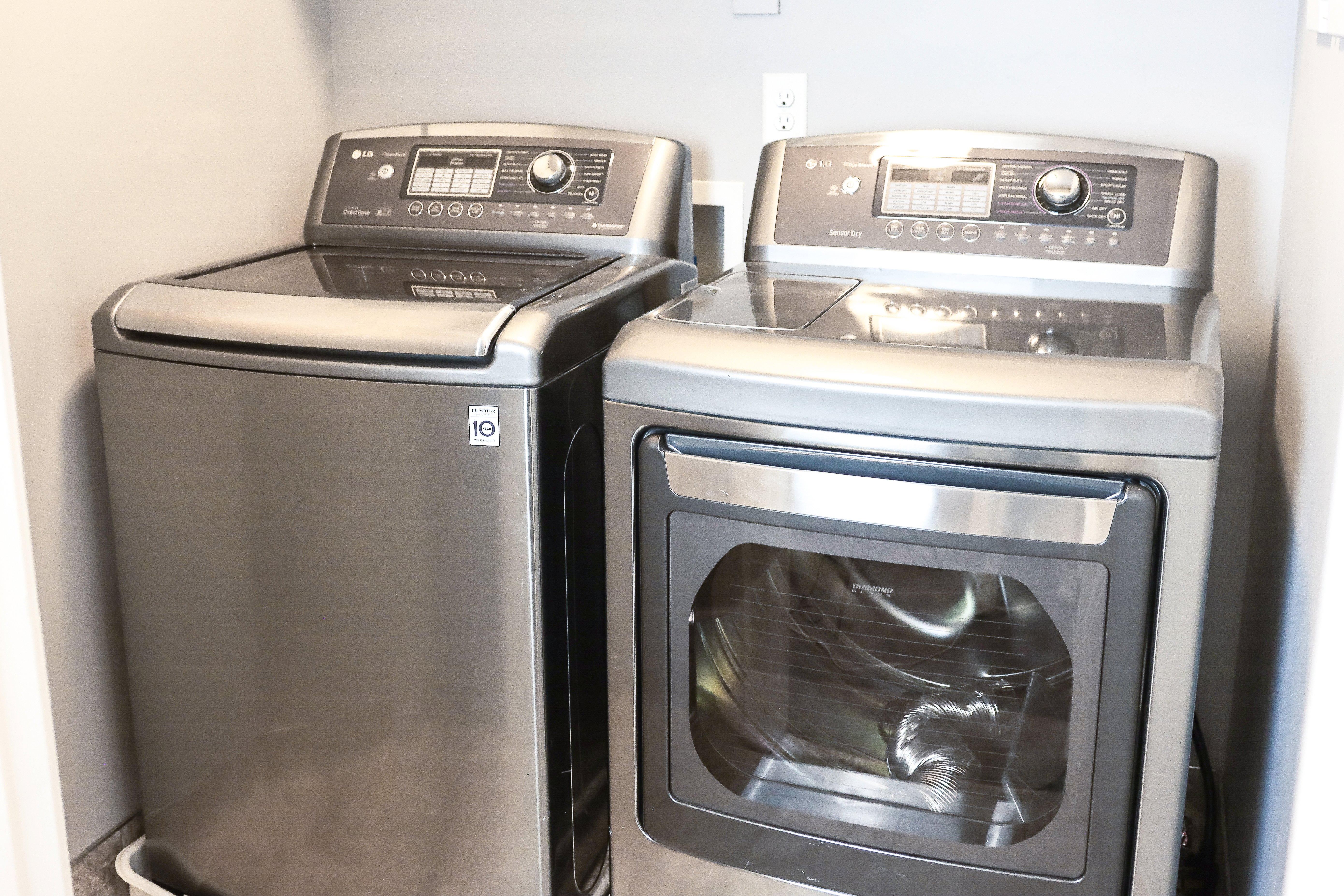 Dedicated laundry area featuring a top-load washer and a front-load dryer, both with stainless steel finishes