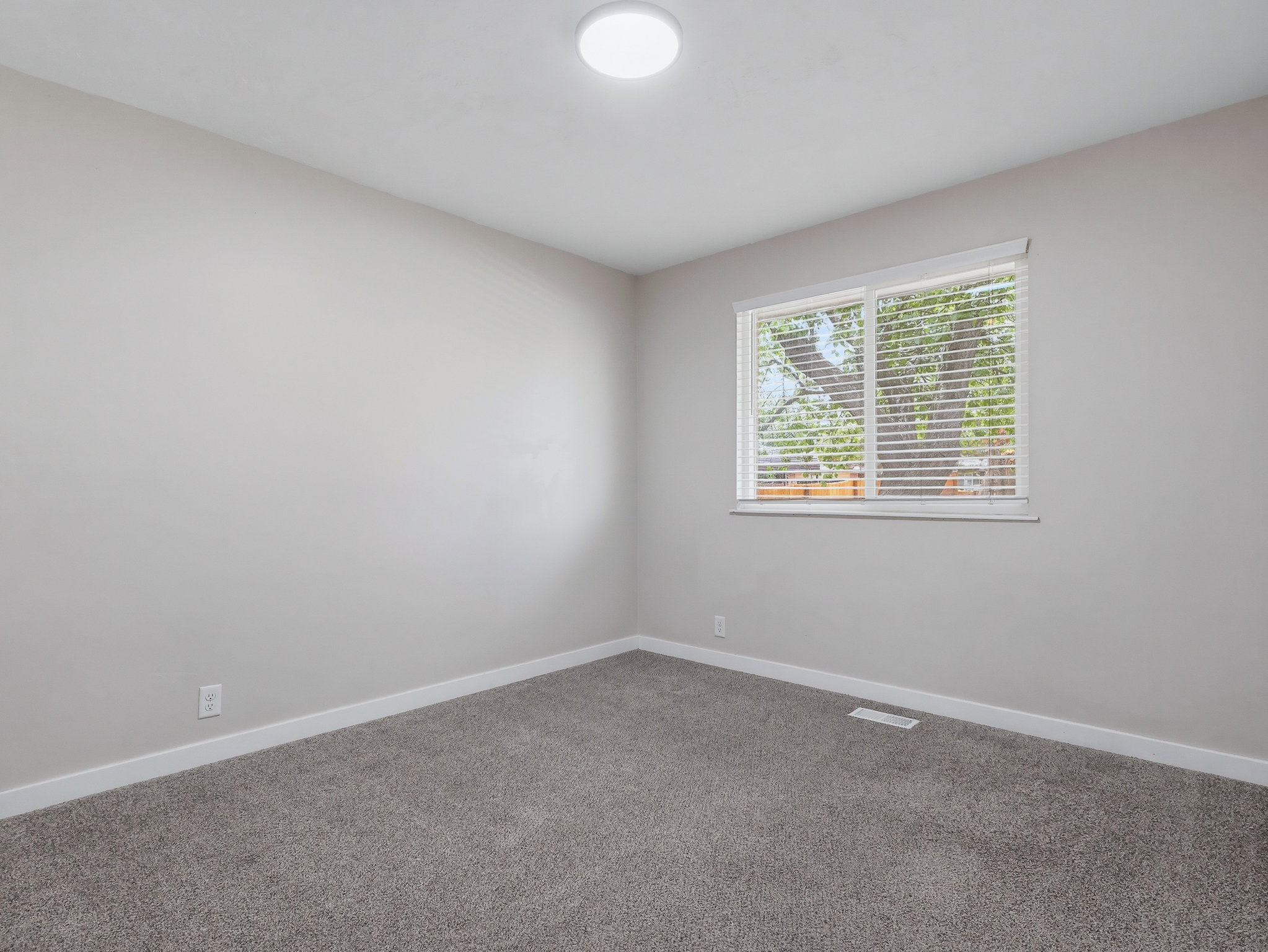 Room featuring light gray wall paint, gray carpet flooring, white trim, a window with blinds, and an overhead flush-mount light fixture