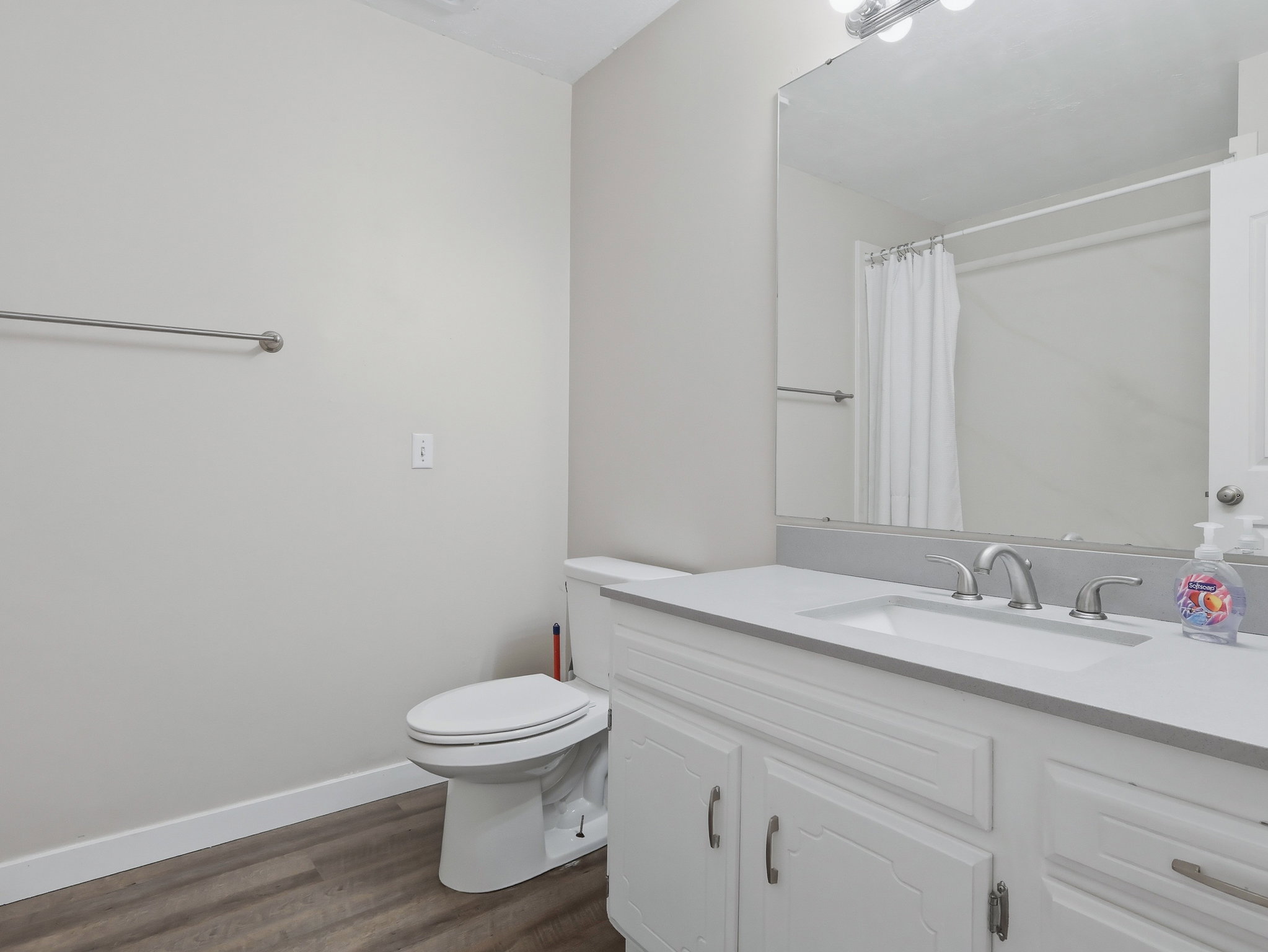 Full bathroom featuring a white vanity with an integrated sink, brushed nickel faucet, and a large wall-mounted mirror