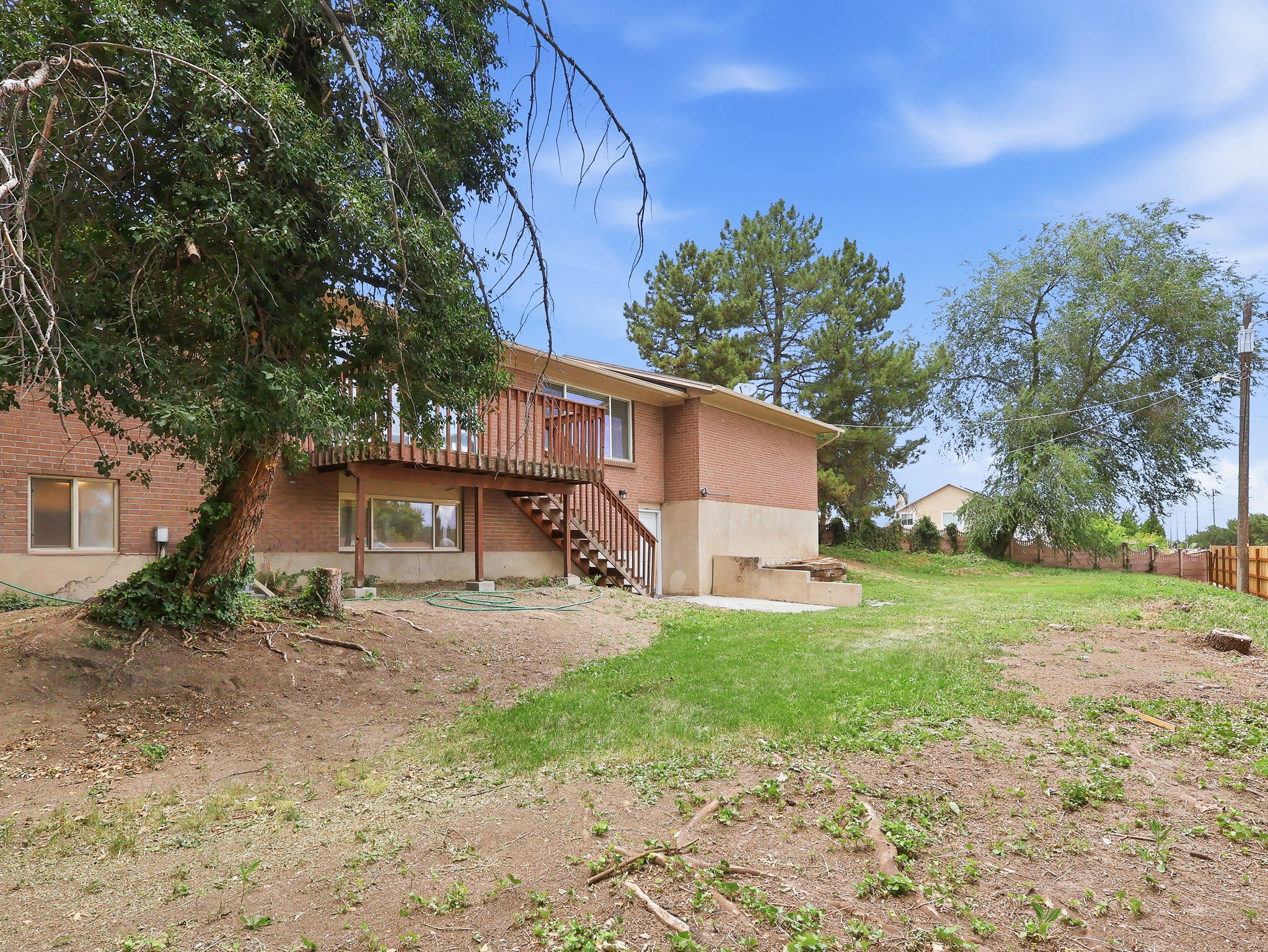 Expansive backyard featuring a red brick exterior, multi-level wood deck, and mature trees