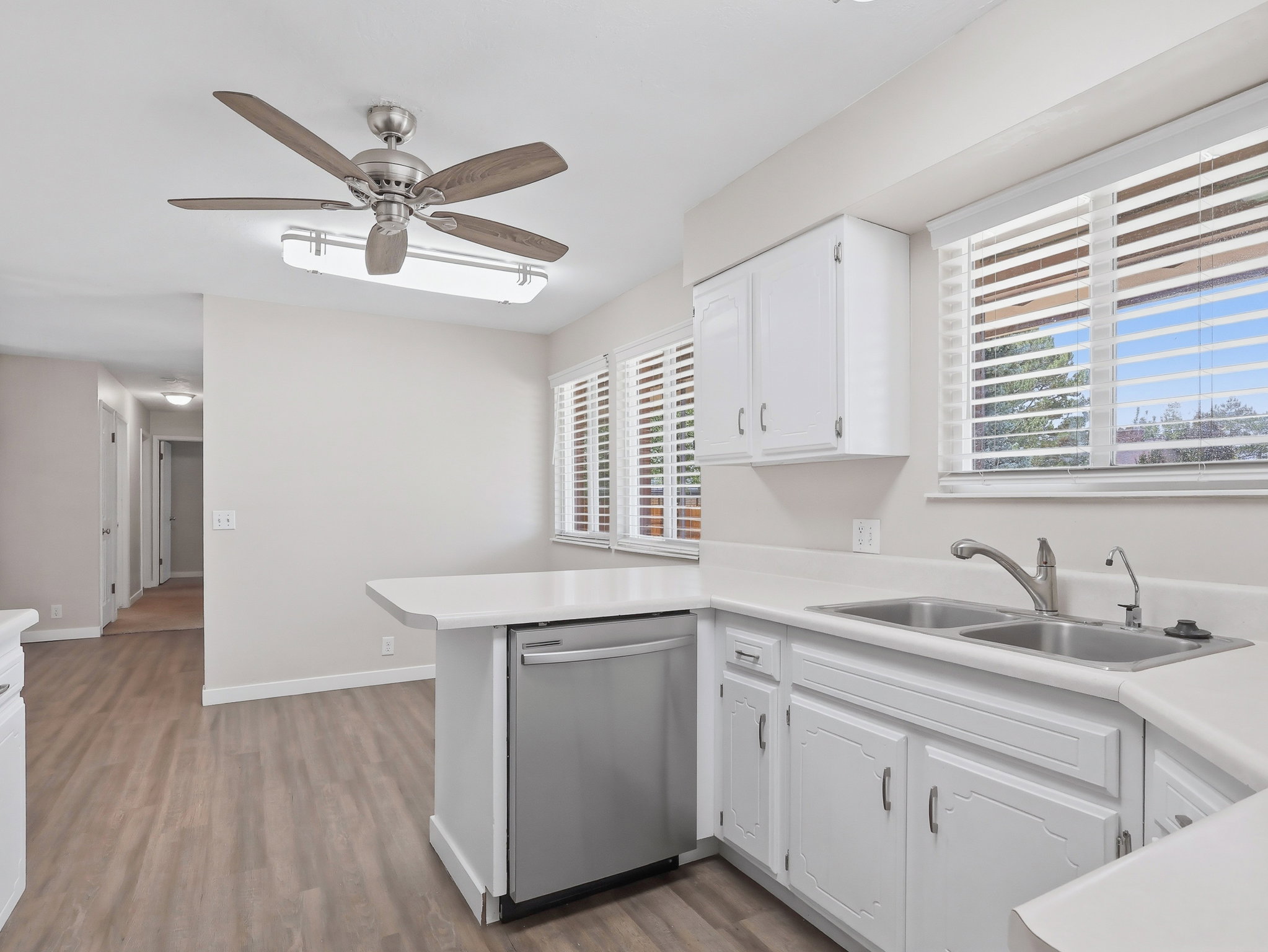 Bright kitchen featuring white cabinetry, a double basin stainless steel sink, and a stainless steel dishwasher