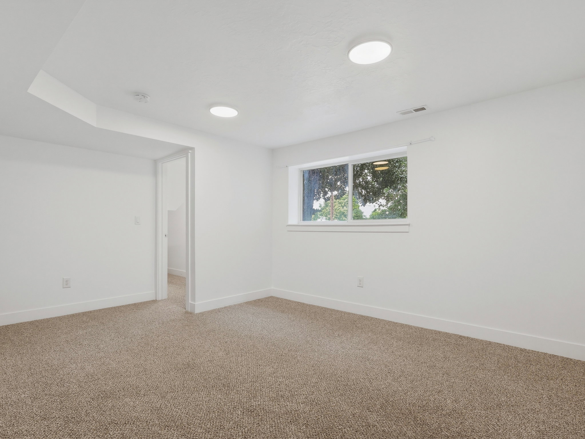 Room featuring neutral-toned carpet flooring, white painted walls, and a single window with white trim