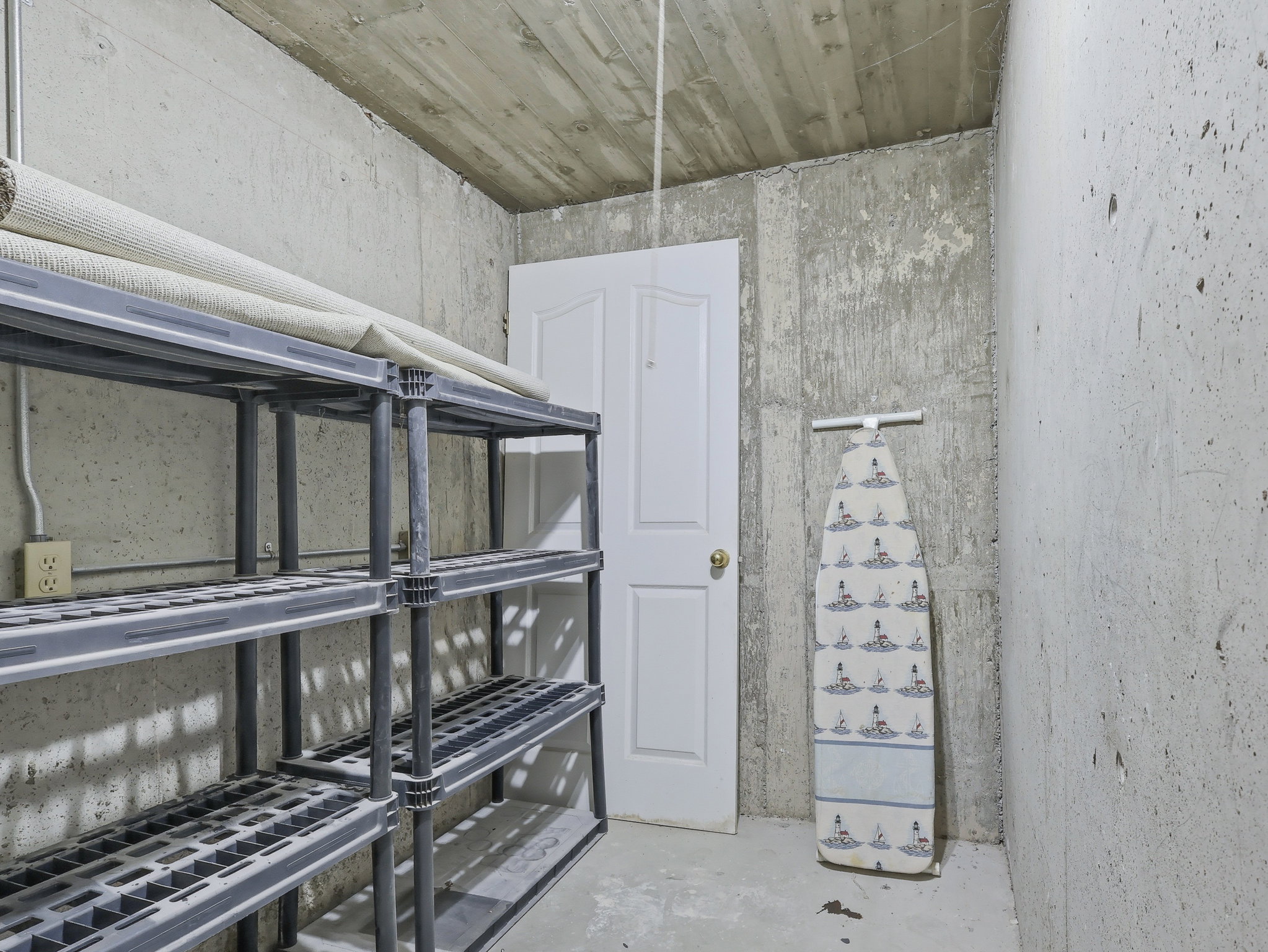 Concrete-finished walls and ceiling, with a paneled door, and visible electrical outlet