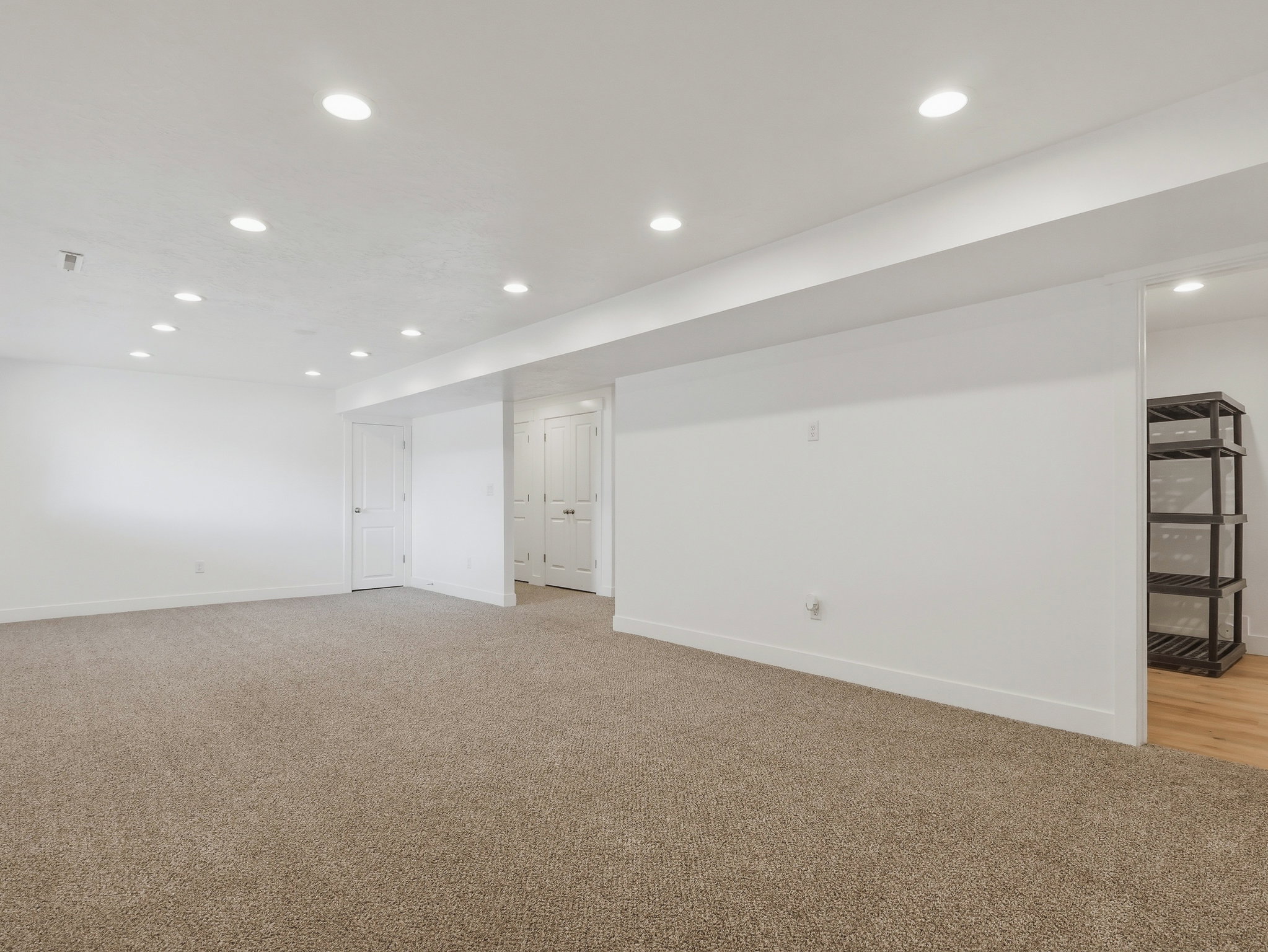 Spacious room featuring neutral carpeting, recessed ceiling lighting, crisp white walls, and white trim
