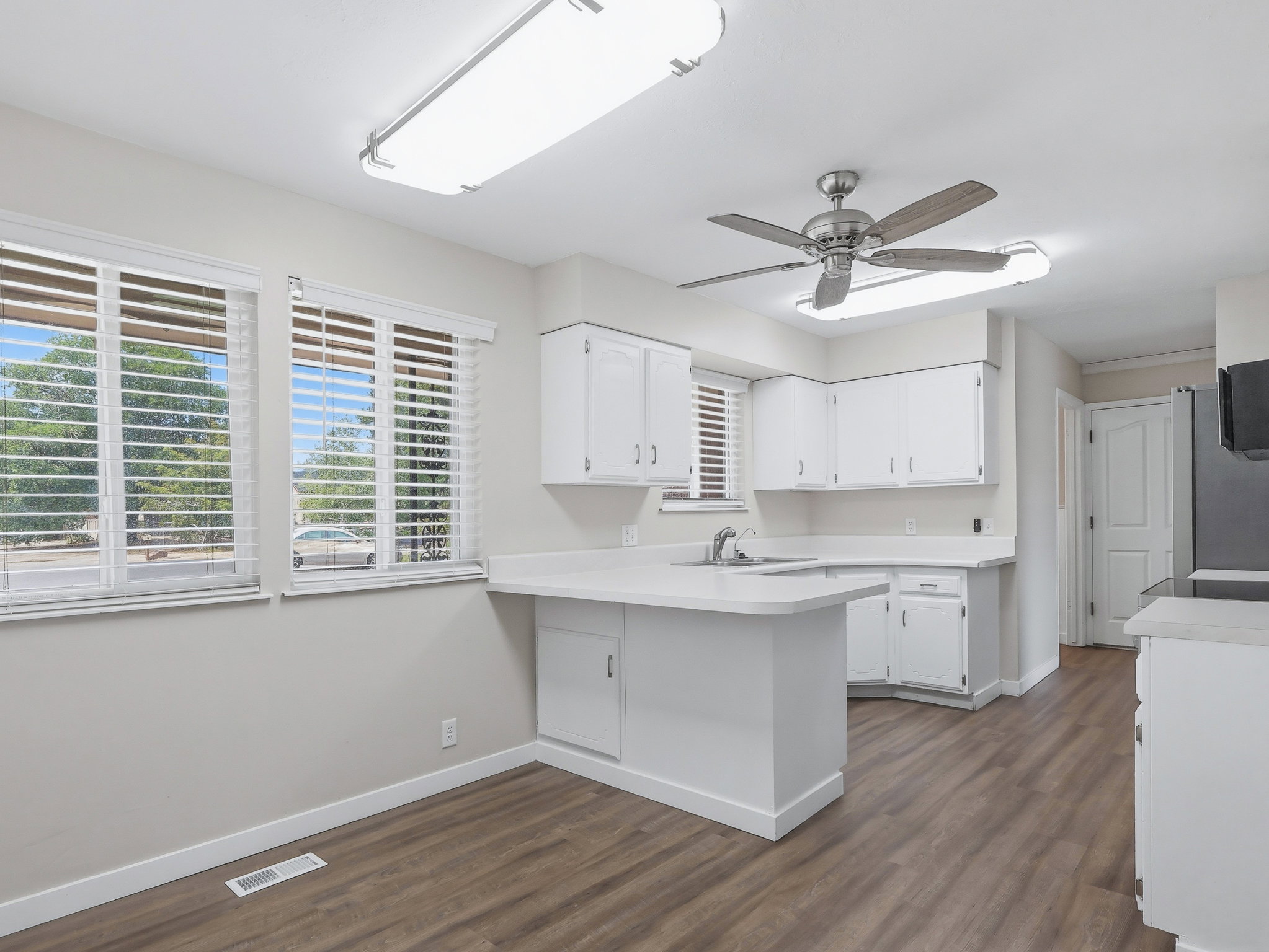 Kitchen featuring white cabinetry, light-toned countertops, and wood-finish flooring