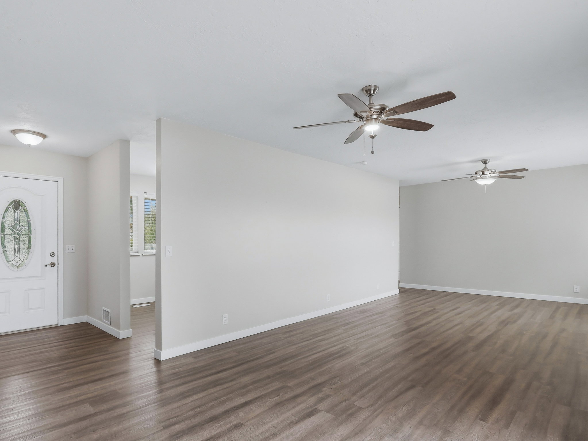 Spacious interior featuring wood-finish flooring, light grey wall paint, and white baseboards