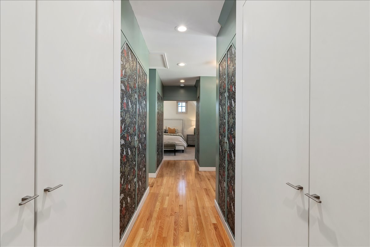 Hallway featuring wood-finish flooring, recessed lighting, and white built-in cabinetry with contemporary hardware