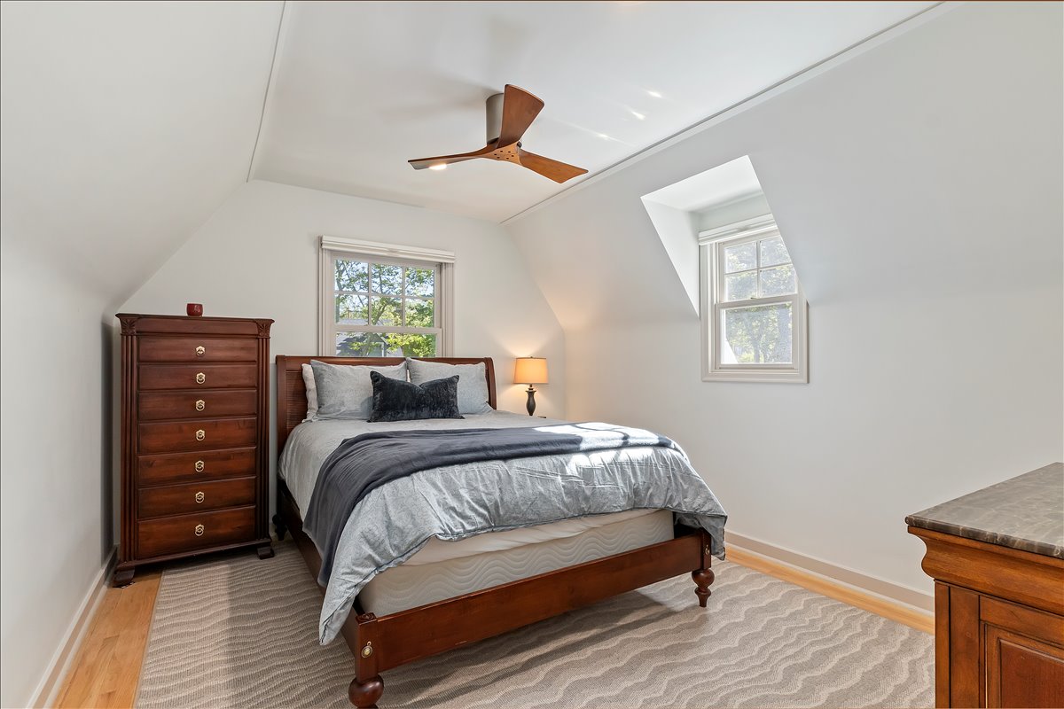 Room featuring sloped ceilings, a ceiling fan, and two windows