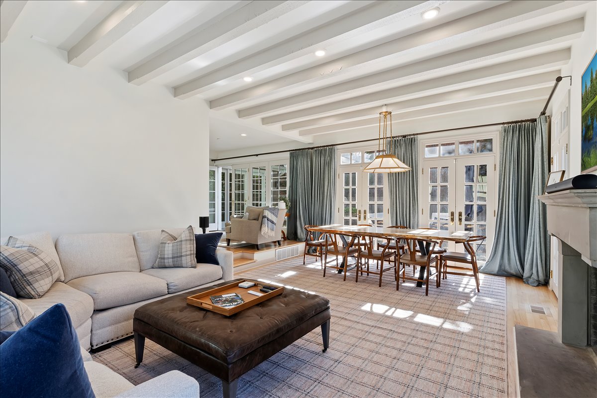 Spacious living area featuring white exposed ceiling beams, recessed lighting, and light wood-finish flooring