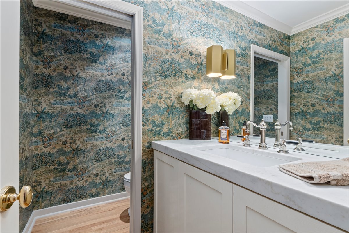 Powder room featuring botanical print wallpaper and crown molding
