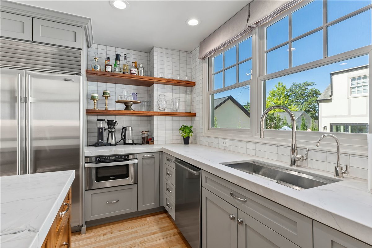 Kitchen featuring white subway tile backsplash, light gray cabinetry, stainless steel appliances, and a double window