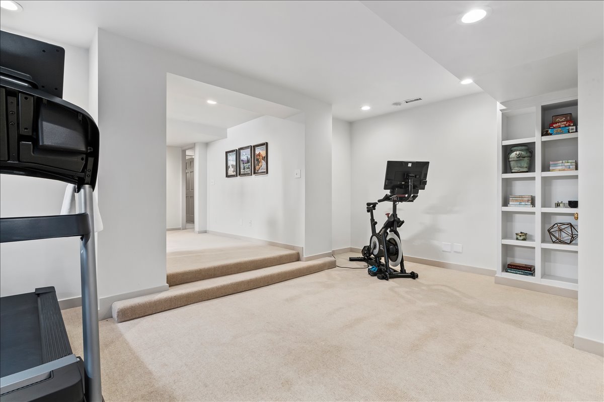Carpeted lower level featuring recessed lighting, built-in shelving, white baseboards, and painted walls