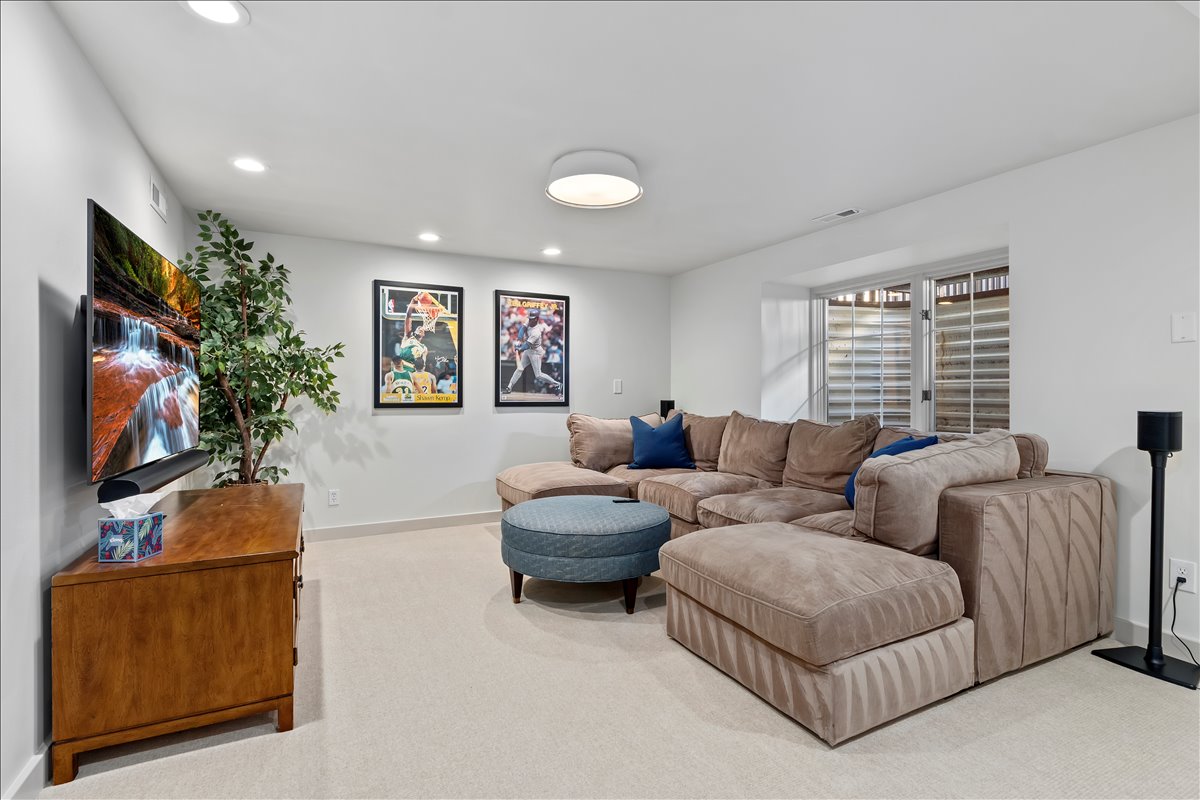 Carpeted living area featuring recessed lighting, a ceiling-mounted light fixture, white walls, and a window with horizontal blinds