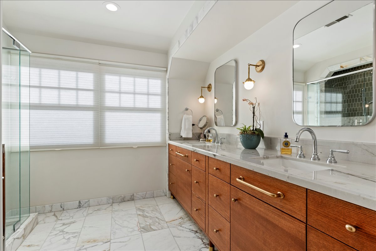 Dual vanity with wood-finish cabinetry, stone-finish countertops, and chrome fixtures