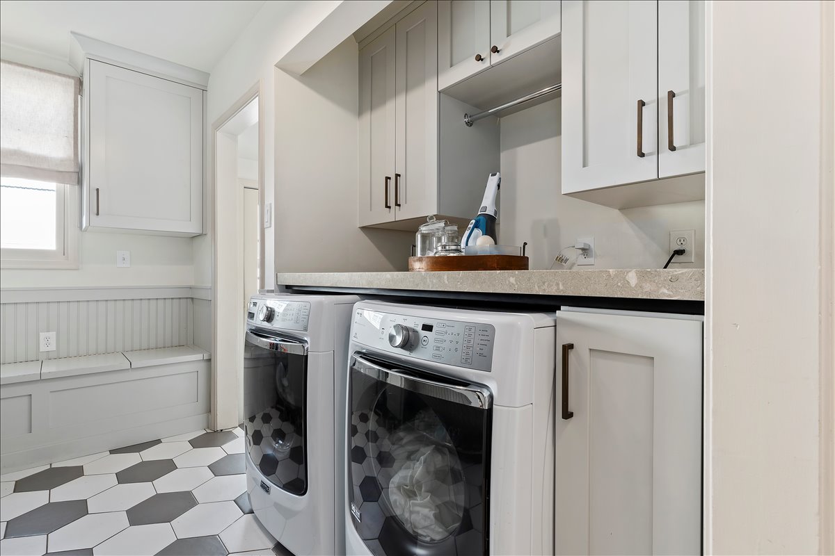 Laundry area featuring a built-in bench, hexagonal floor tiling, and upper and lower cabinetry