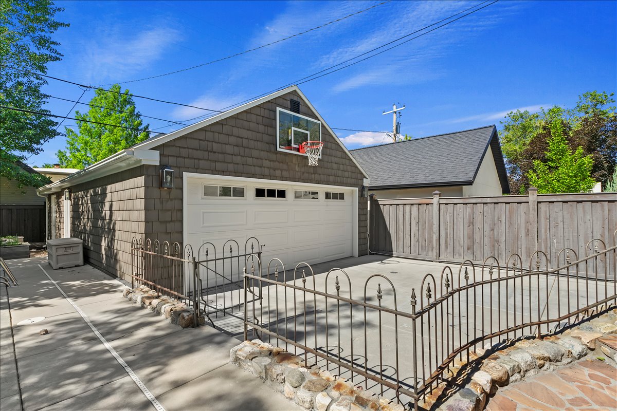 Detached garage with shaker shingle siding and a white panel garage door
