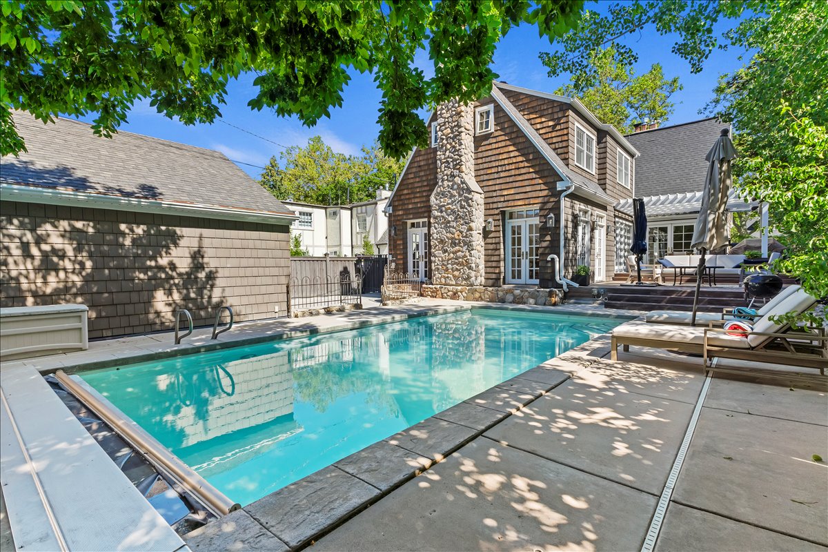 Rectangular swimming pool with integrated cover, surrounded by stone coping and a concrete patio