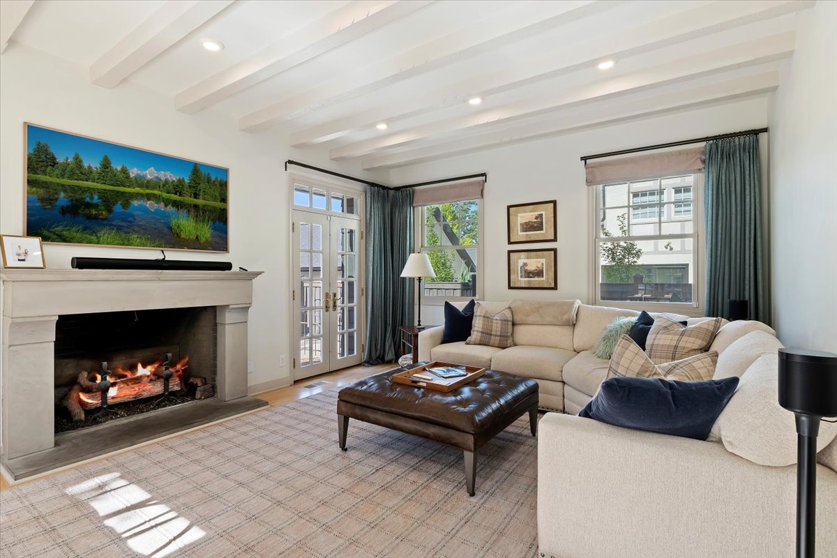 Living area featuring a stone fireplace, recessed lighting, and exposed ceiling beams