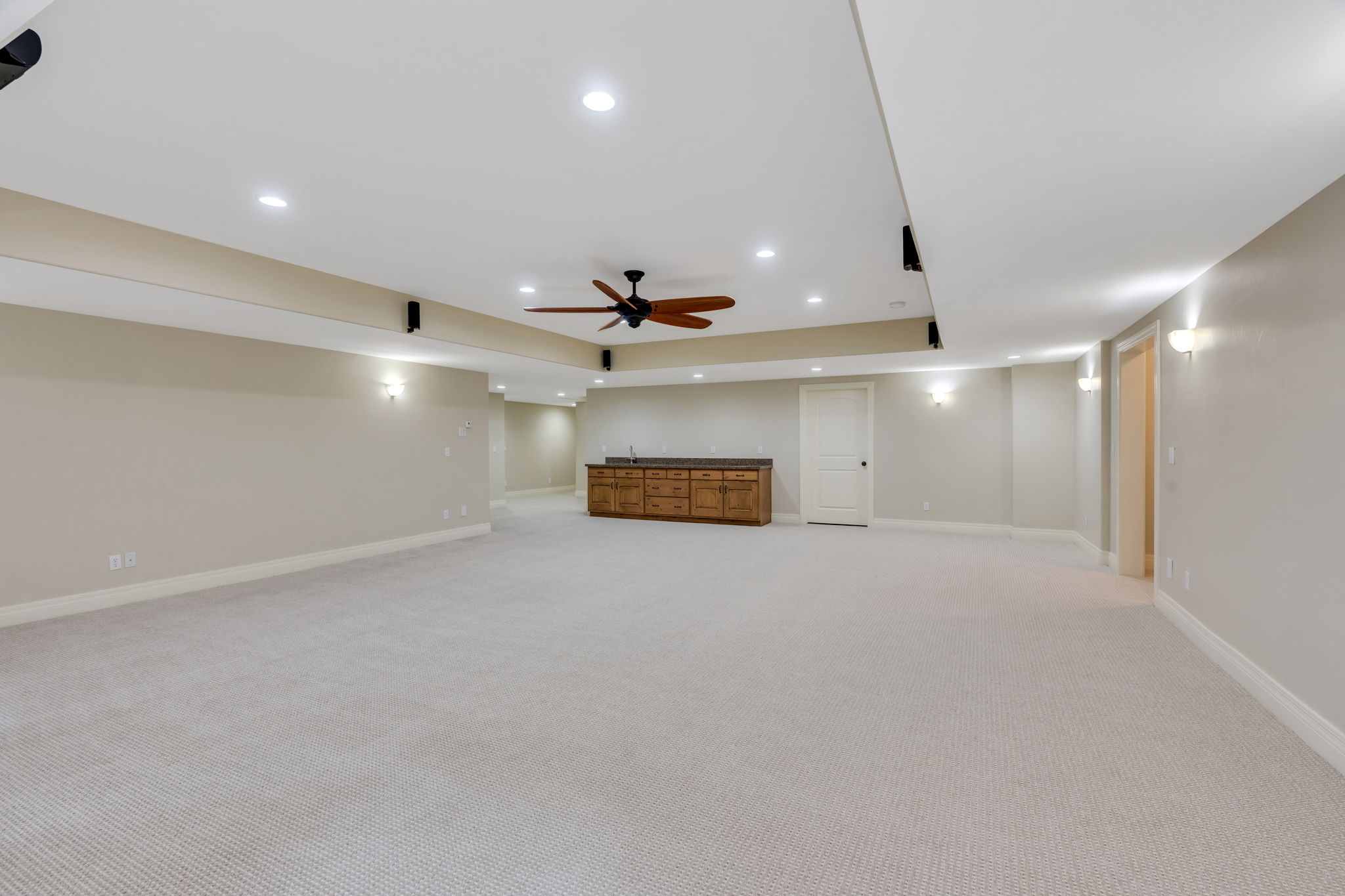 Another view of spacious room featuring light-toned carpeting, recessed lighting, and a ceiling fan and wet bar