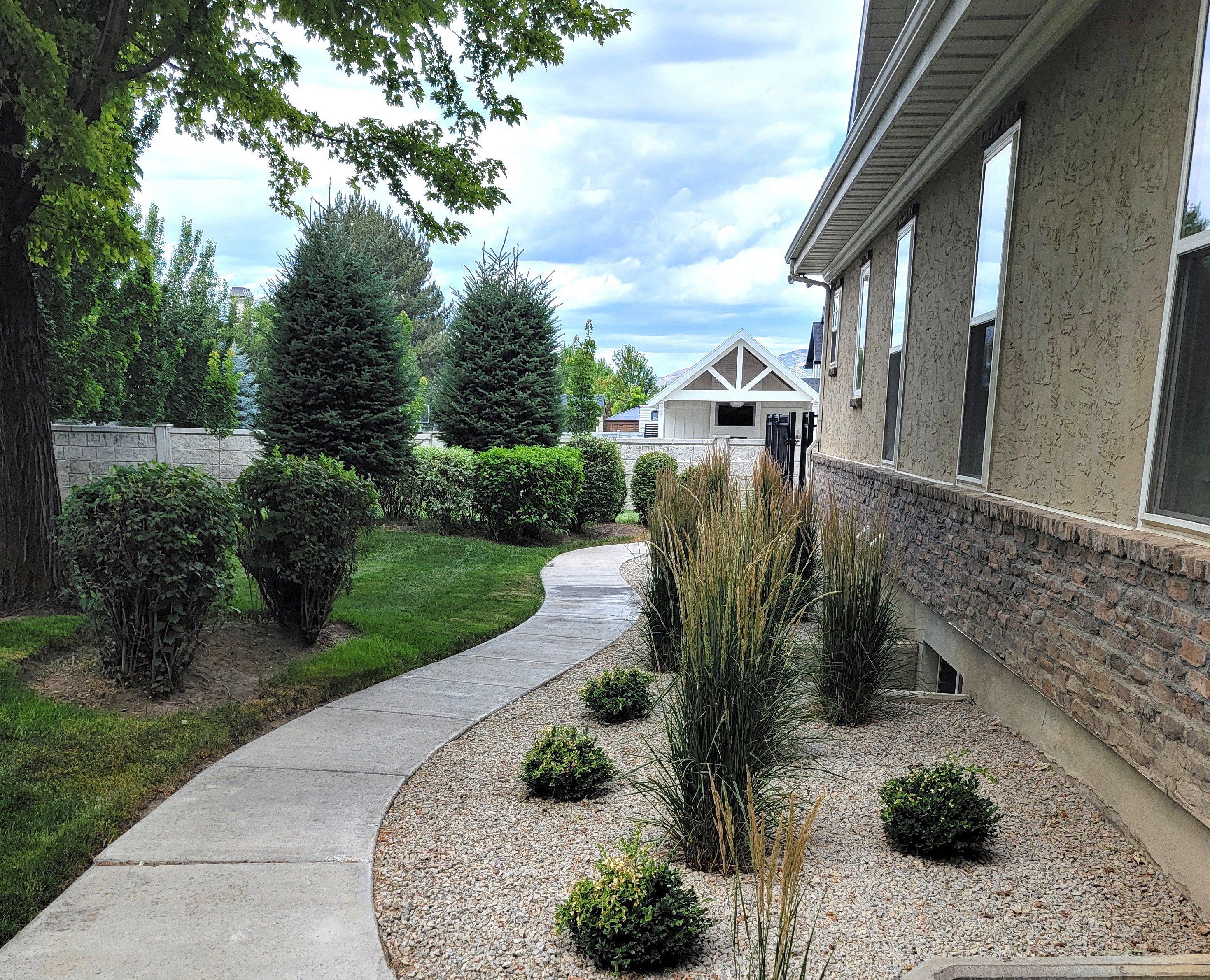 Curved concrete pathway bordered by manicured lawn and mature landscaping