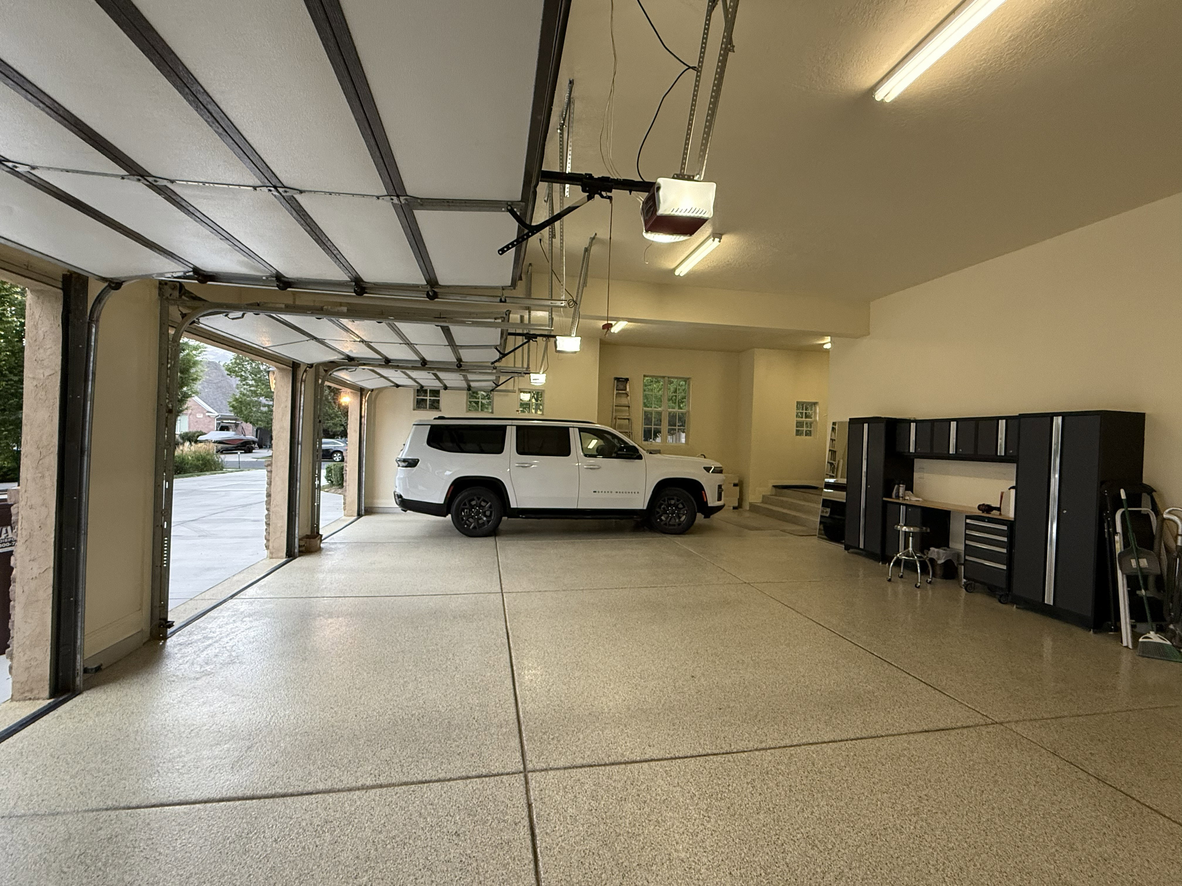 Spacious garage with epoxy-coated flooring, and overhead fluorescent lighting