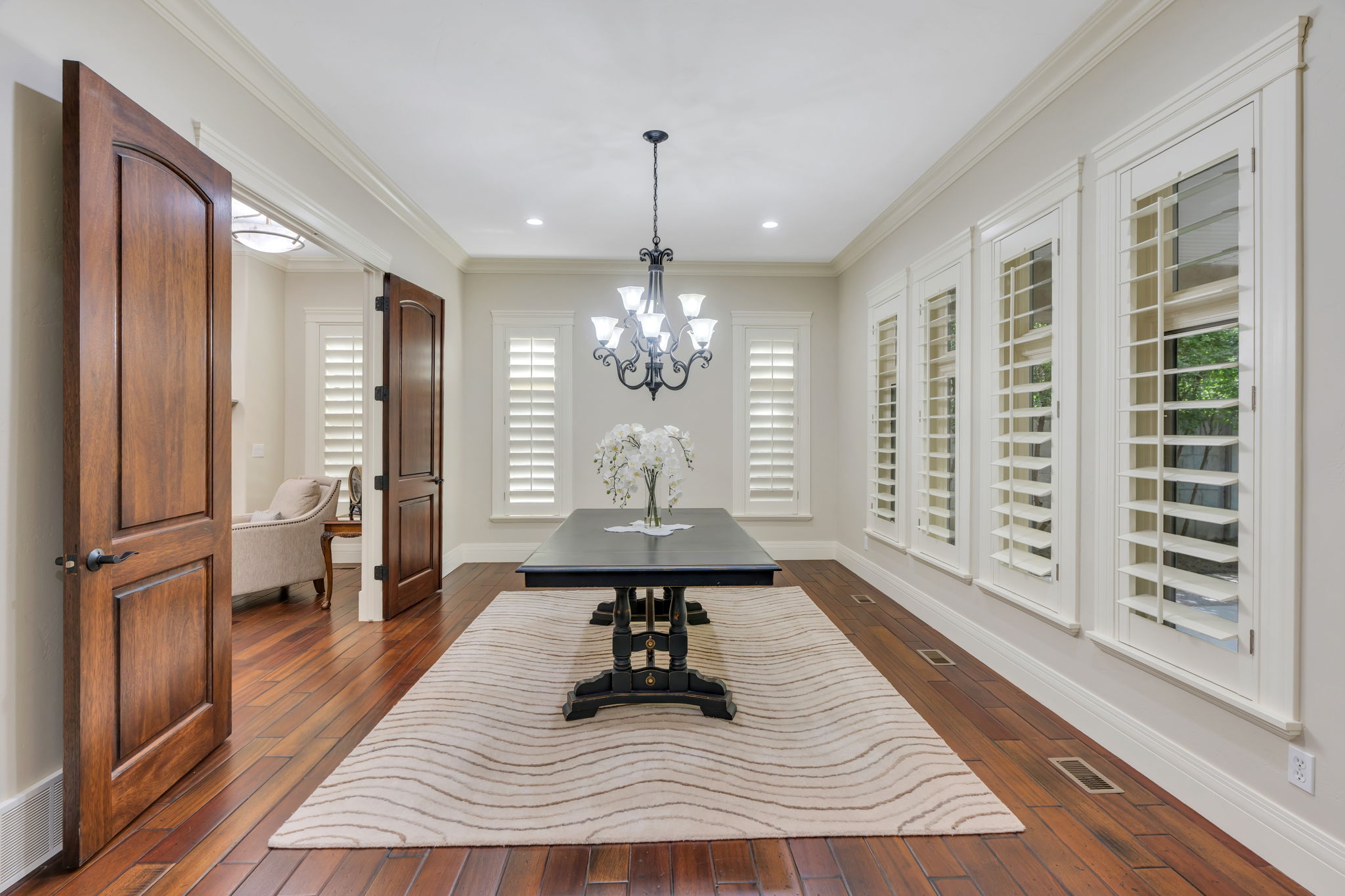 Dining/flex room featuring rich wood-finish flooring, plantation shutters, crown molding, a decorative chandelier, and recessed lighting