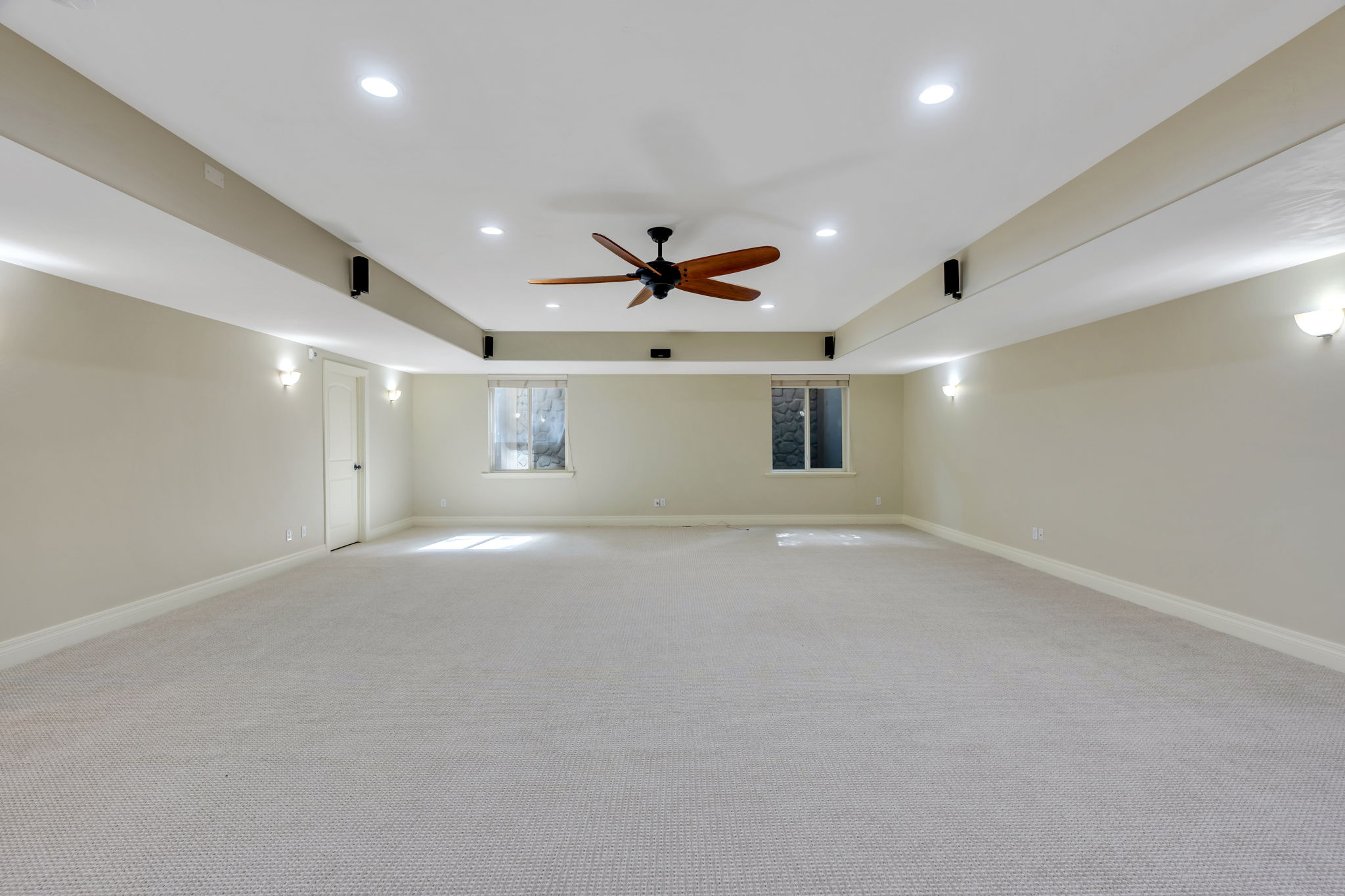 Spacious room featuring neutral carpeting, recessed lighting, a ceiling fan with wood-finish blades, and built-in wall speakers, and radiant heat in floor