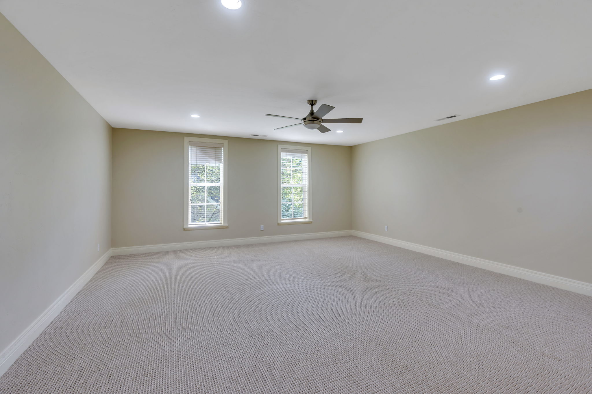One of two spacious upstairs bedrooms featuring neutral carpeting, recessed lighting, a ceiling fan, two double-hung windows, and light-toned walls and large closets