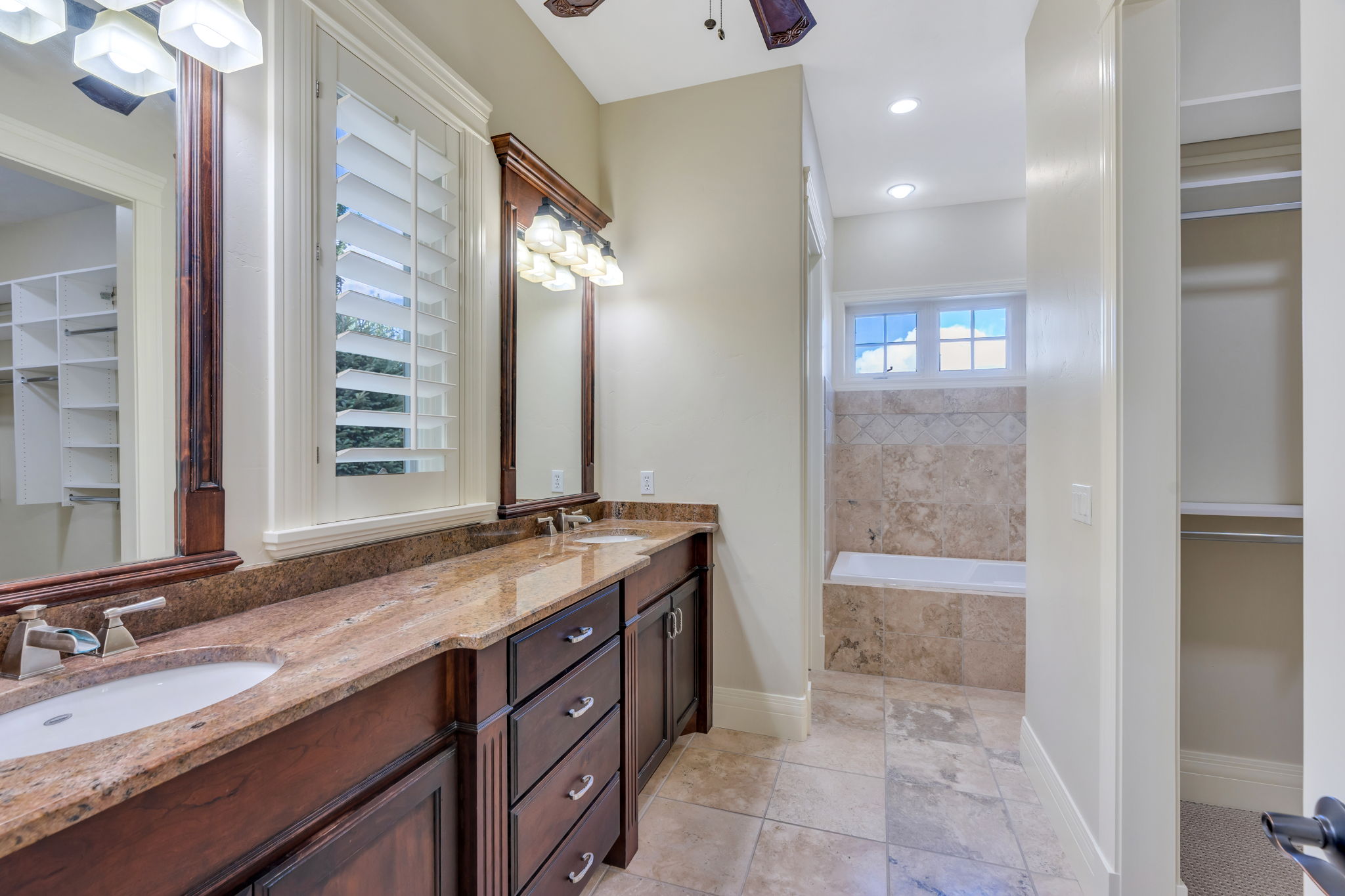 Primary bathroom featuring a double vanity with stone countertops, integrated sinks, and dark wood cabinetry