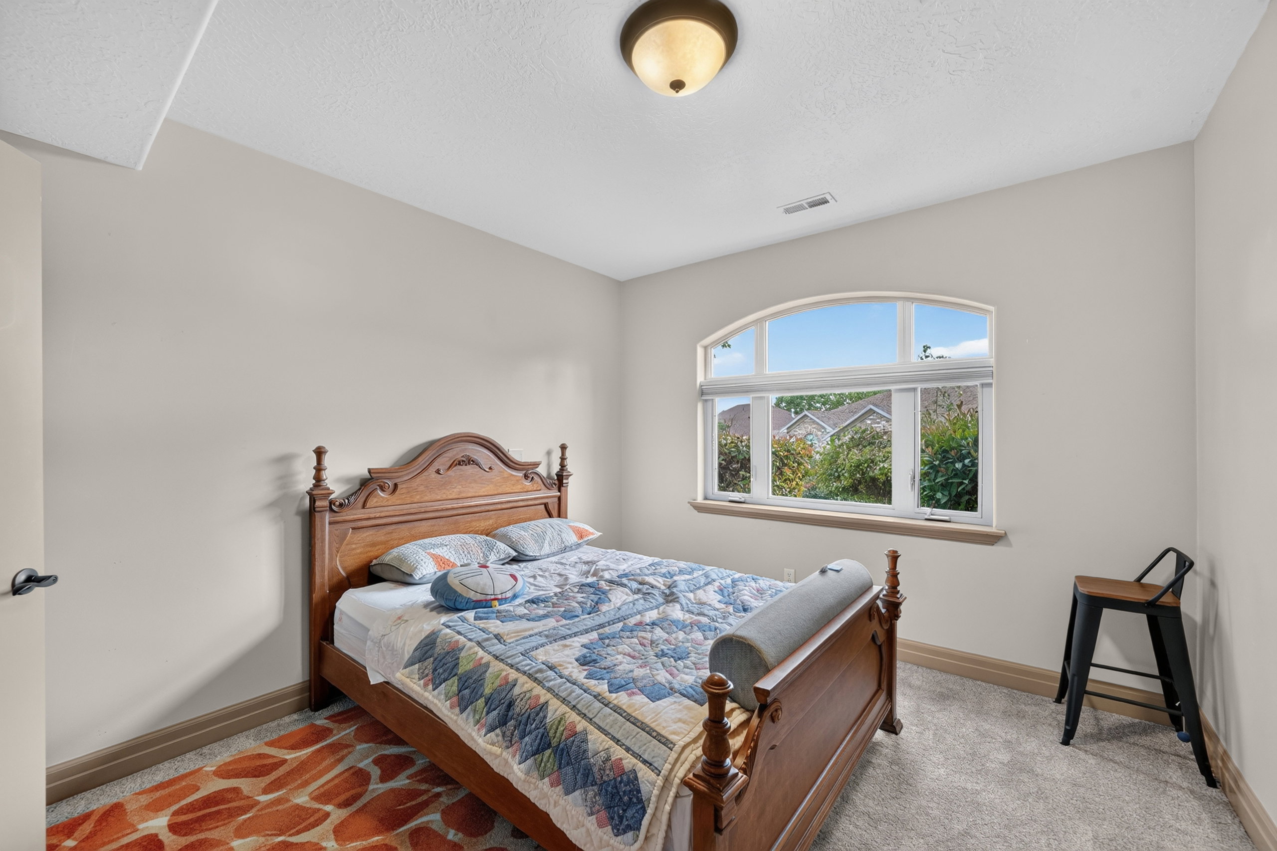 Arched window with multiple panes, light neutral wall paint, and gray carpet flooring