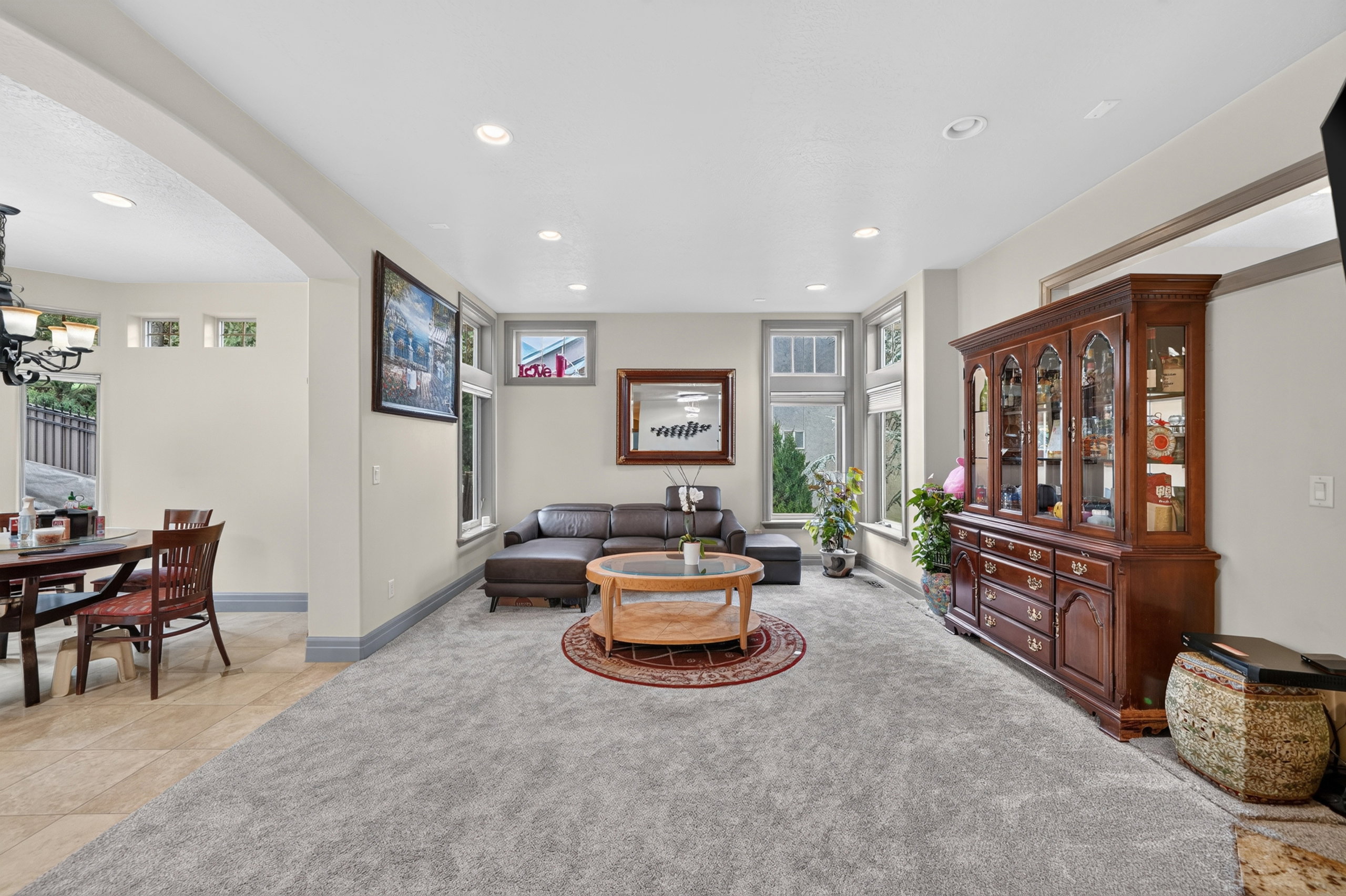 Spacious living area featuring light gray carpeting, recessed lighting, and multiple windows