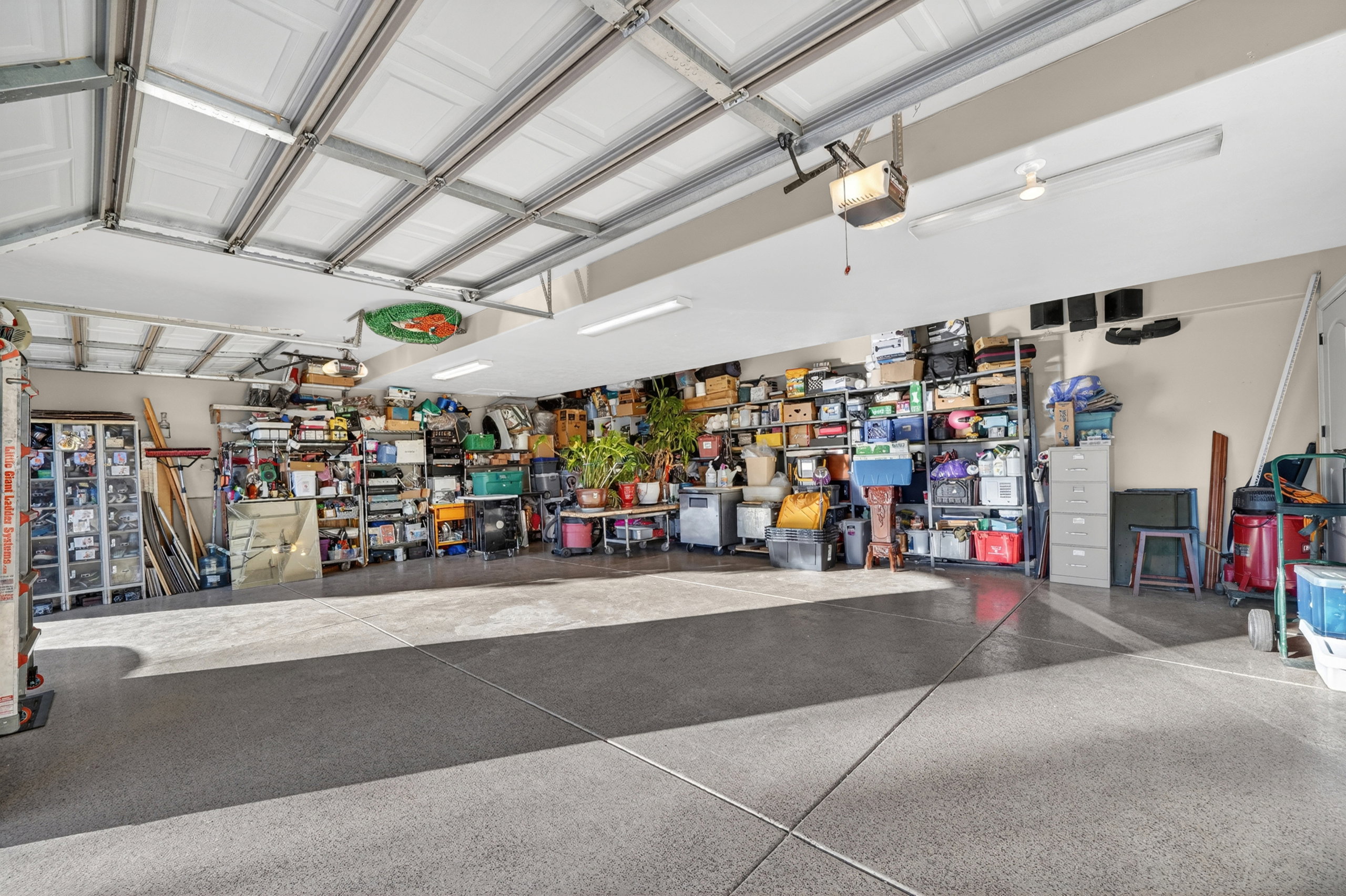 Spacious garage featuring a durable epoxy floor, overhead fluorescent lighting, and multiple garage doors