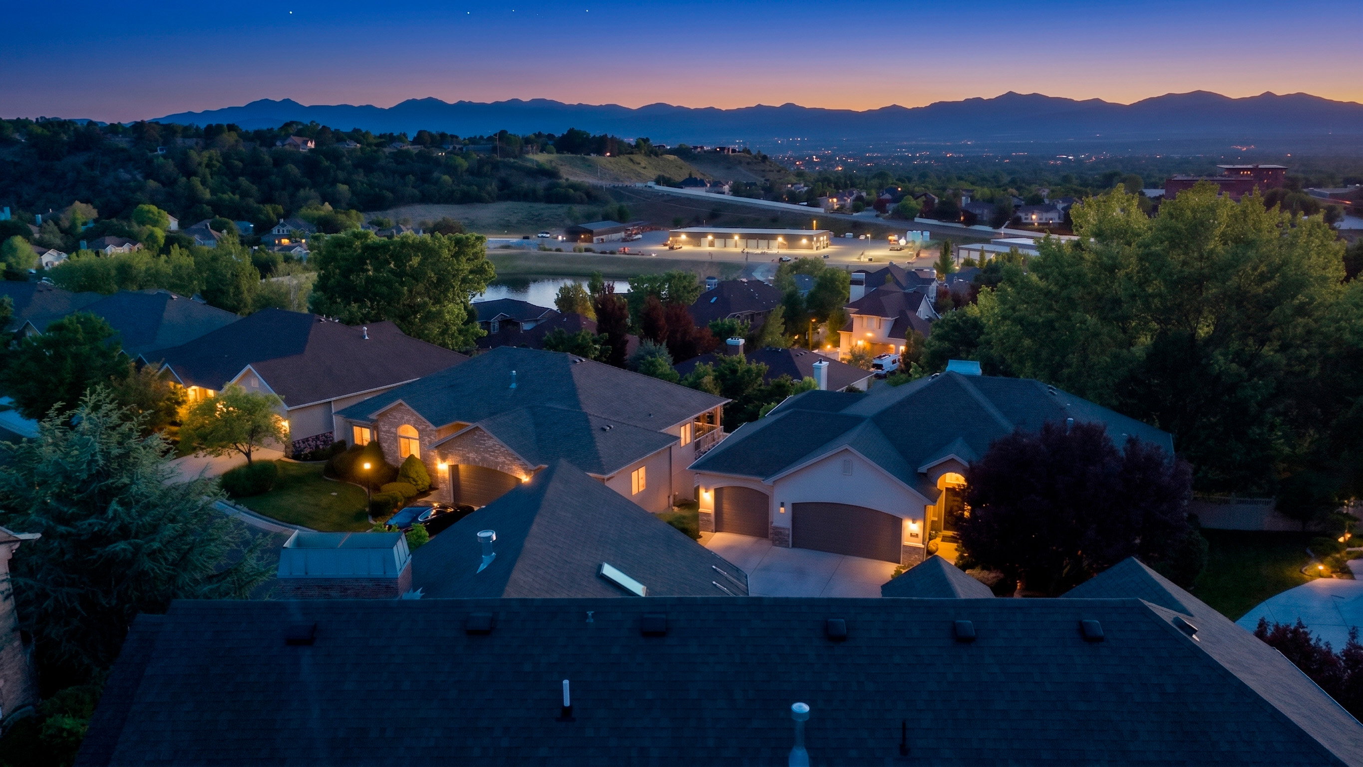 Aerial perspective showcasing a residential neighborhood with distant mountain ranges and a body of water