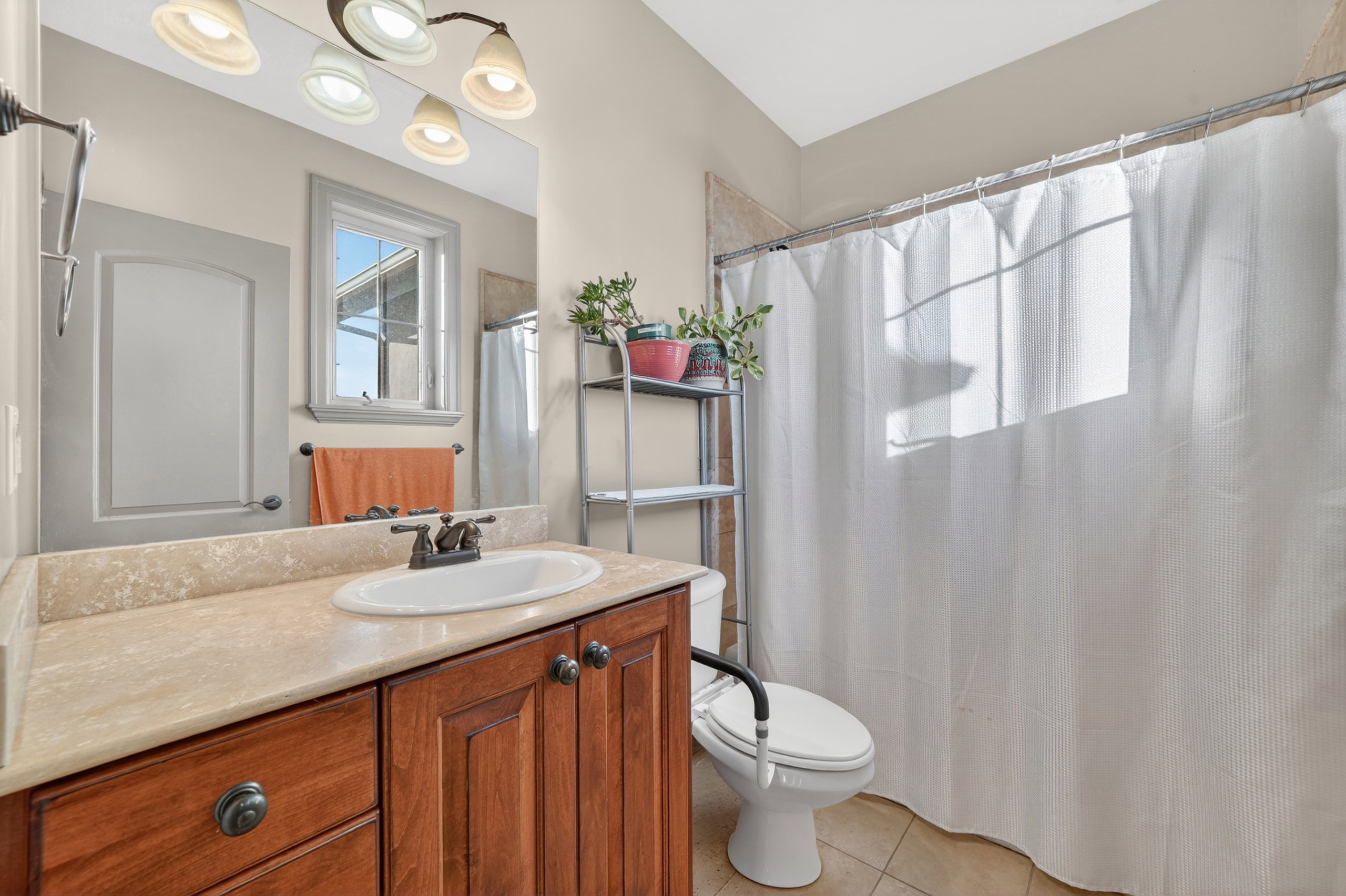 Bathroom featuring a wood vanity with an integrated oval sink, a light-colored countertop, overhead vanity lighting, and tiled flooring