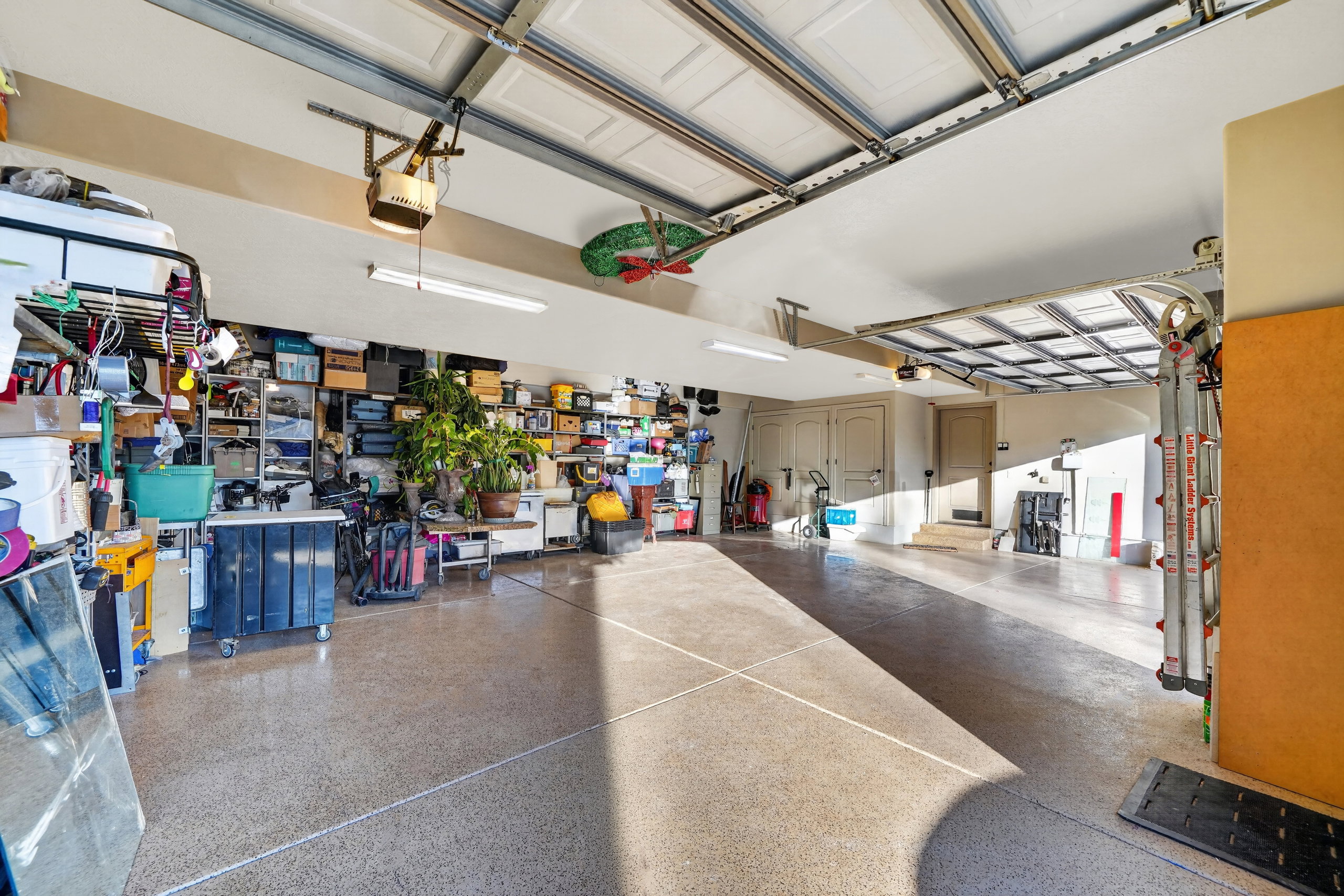 Spacious garage with epoxy-coated concrete flooring, dual overhead garage doors, and built-in shelving