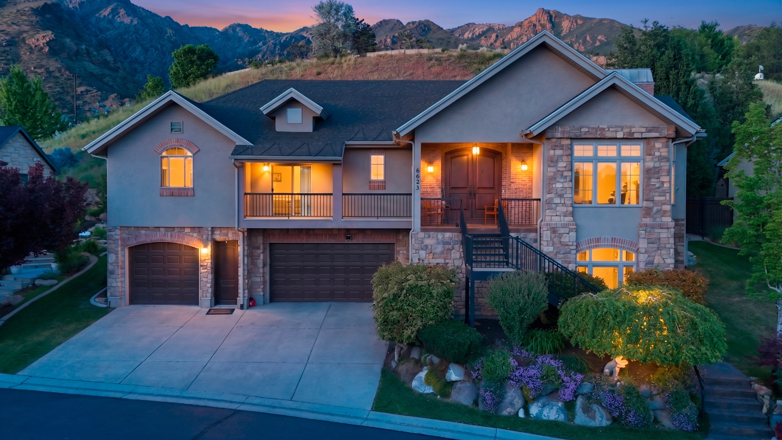 Stucco and stone exterior featuring a two-car garage, a separate single-car garage, and a covered main entry with double doors