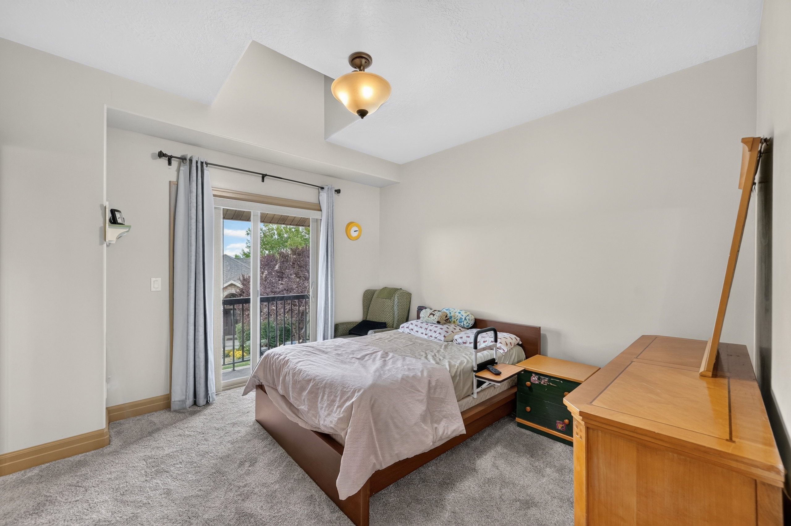 Carpeted bedroom featuring a tray ceiling, recessed lighting, and a sliding glass door opening to a private balcony with black railings