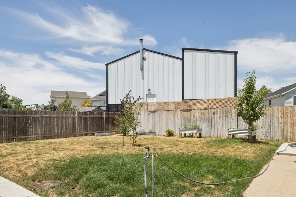 Spacious backyard featuring a wood privacy fence, mature and young trees, and two raised garden beds