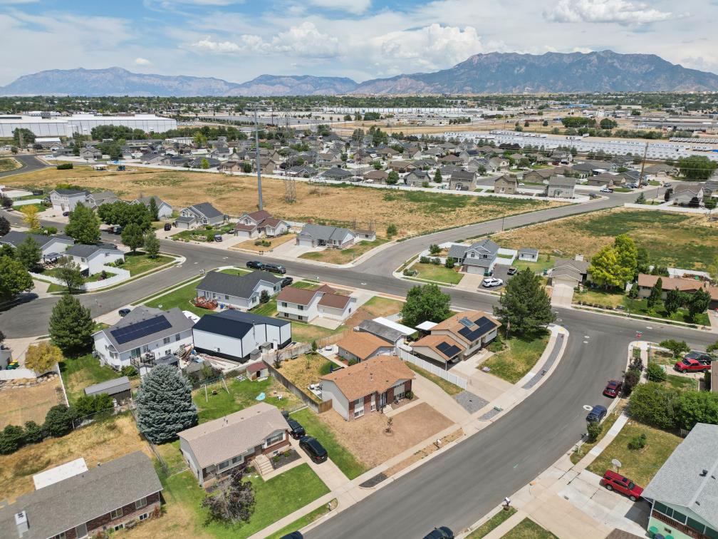 Residential neighborhood featuring a variety of single-family homes, mature trees, and mountainous terrain in the background